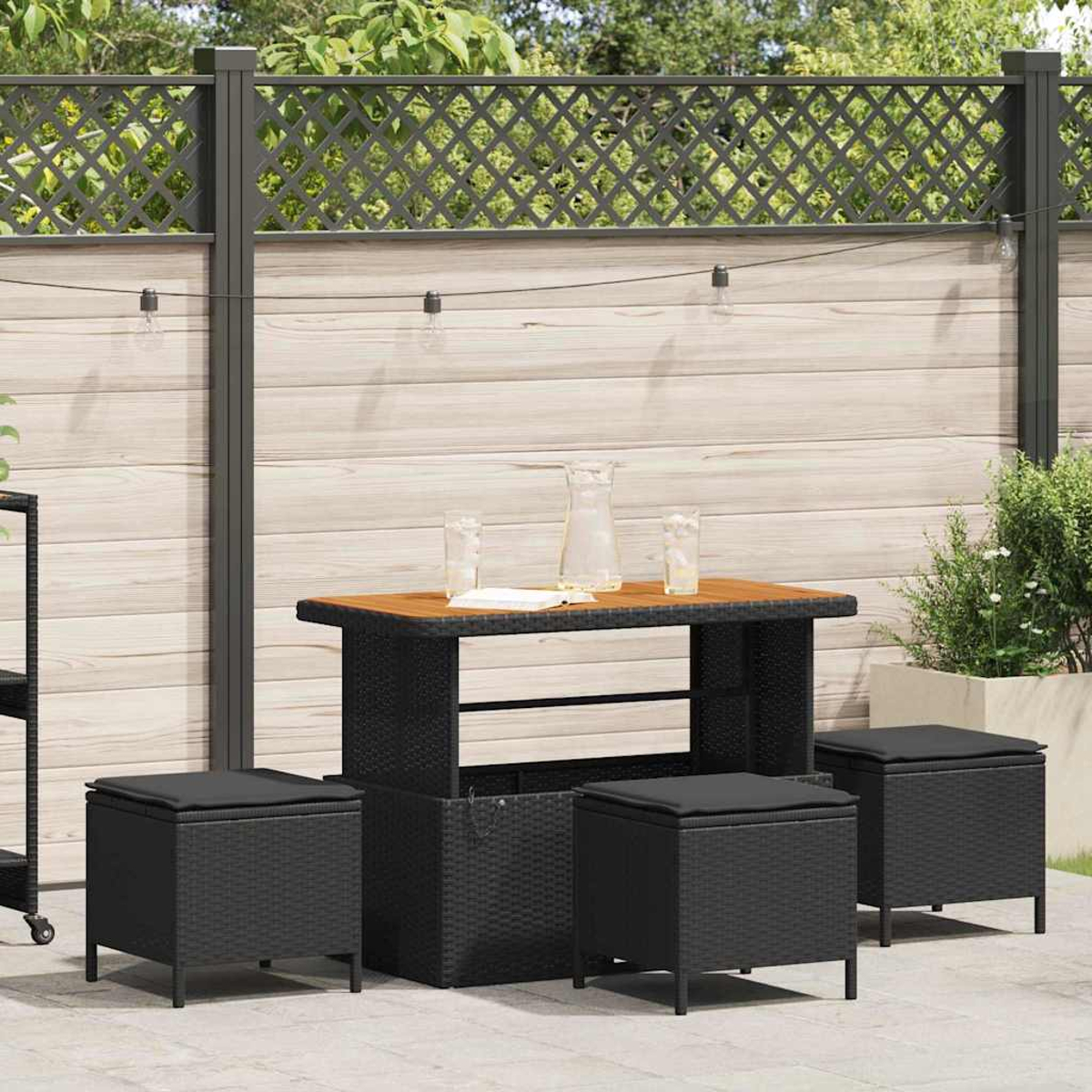 Garten-Terrassenset mit Tisch, Hockern und Holzzaun im Hintergrund. Enthält Gläser, Kanne und Lichterketten.