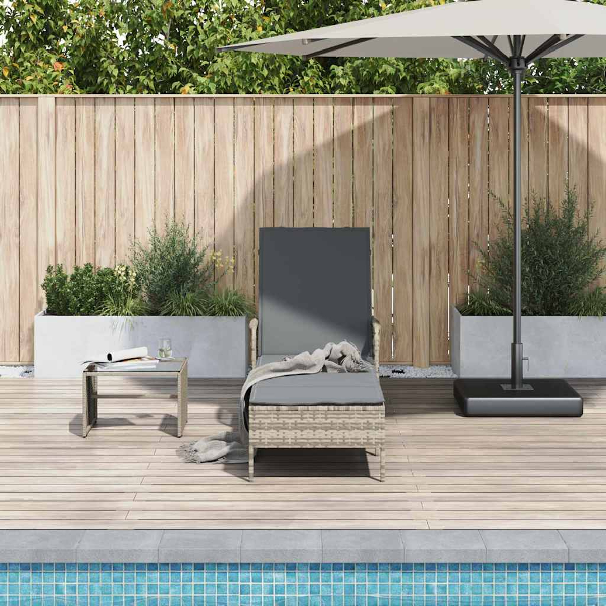 Eine Terrasse mit Liegestuhl, Beistelltisch und Sonnenschirm. Ein Holzzaun und Pflanzen befinden sich im Hintergrund, ein Pool ist sichtbar.
