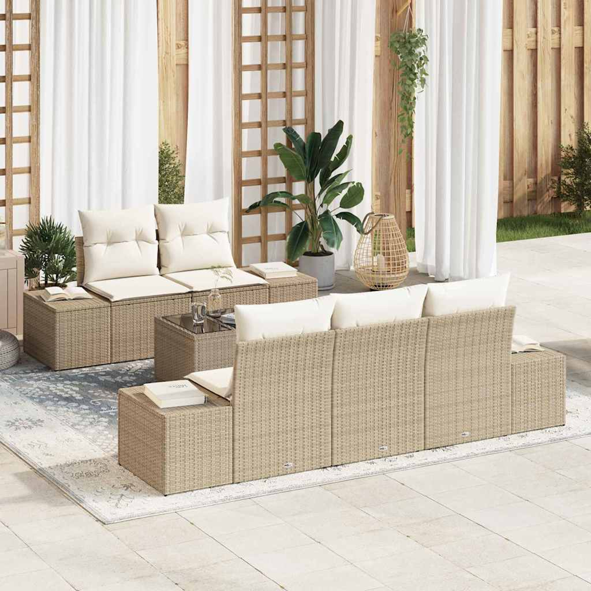 Juego de muebles de mimbre para exteriores con cojines blancos y una mesa de cristal. Una planta y cortinas al fondo.