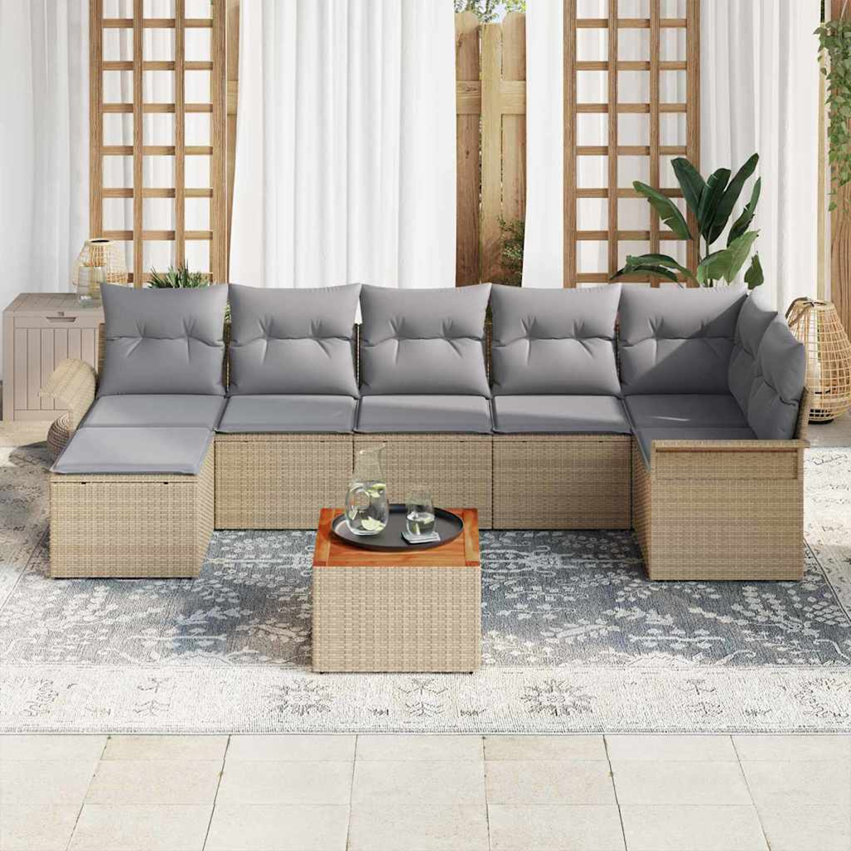 Outdoor-Ecksofa mit grauen Kissen, einem kleinen Tisch mit Tablett und einem gemusterten Teppich auf einer Terrasse. Weiße Vorhänge im Hintergrund.