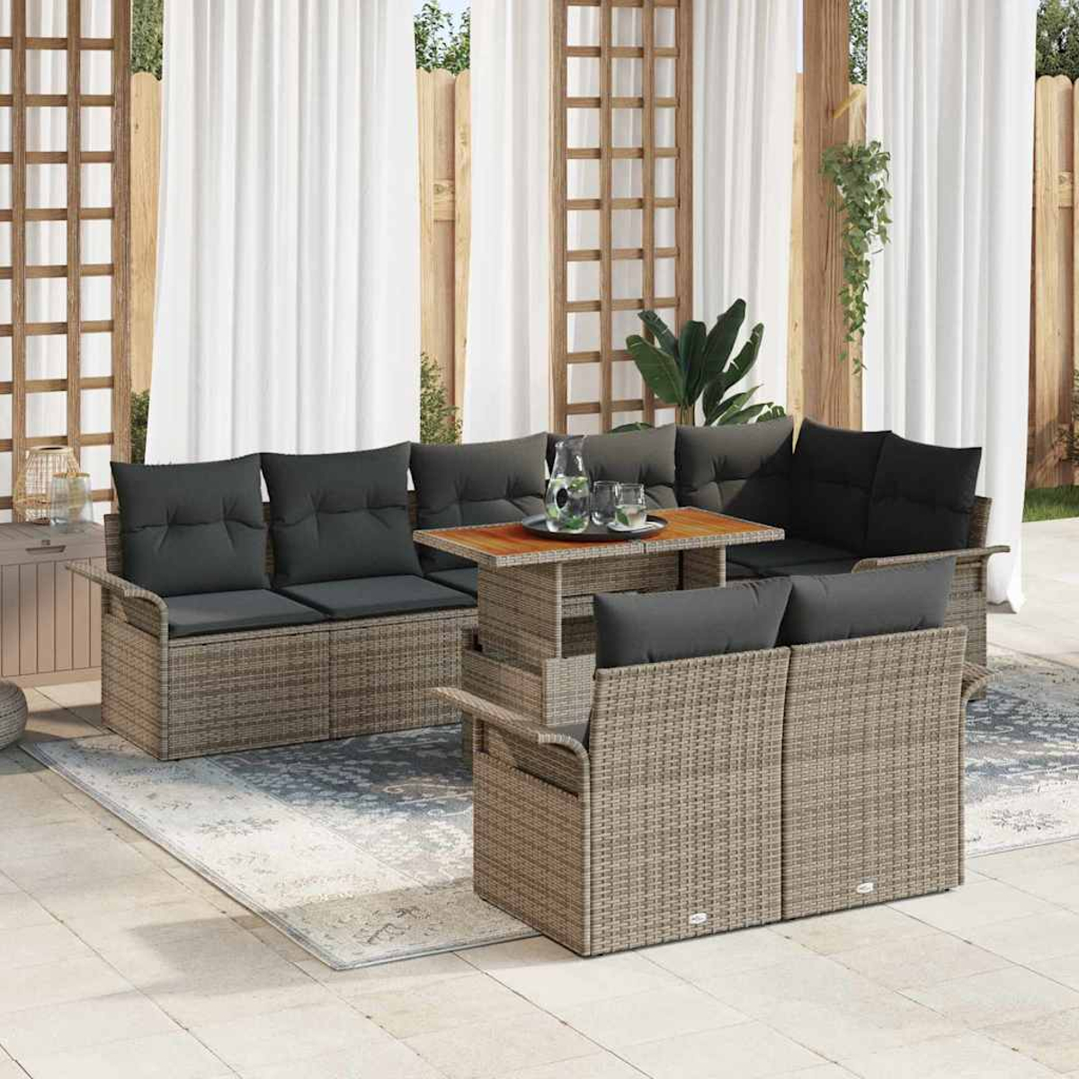Gartenmöbel-Set aus Korbgeflecht mit grauen Kissen, einem Holztisch und weißen Vorhängen im Hintergrund, das eine gemütliche Terrasse schafft.