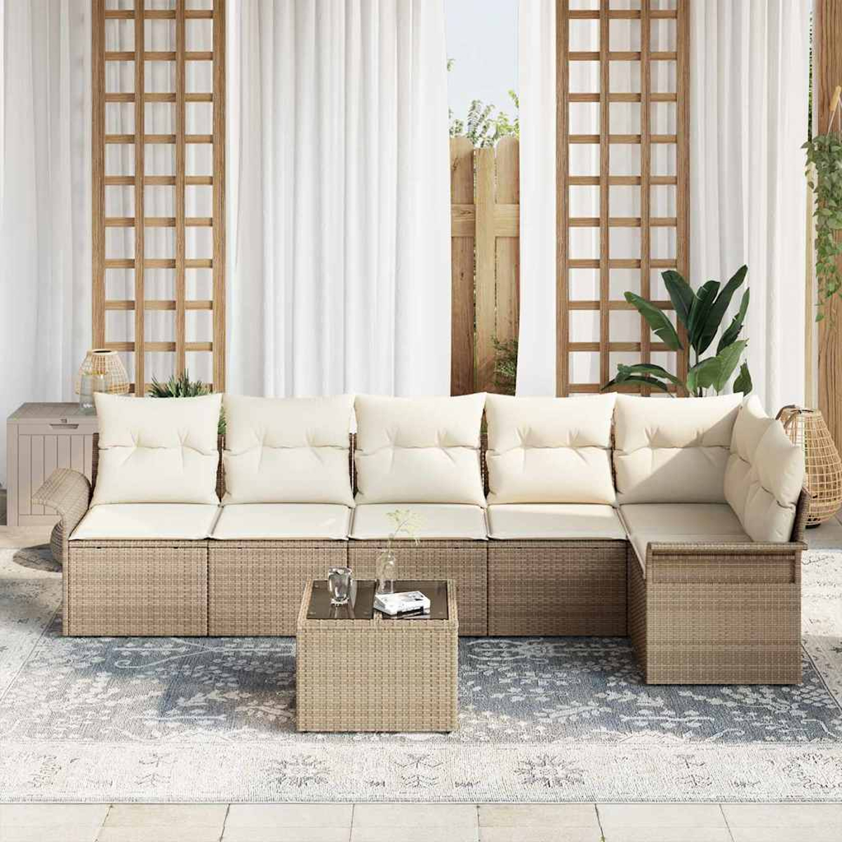 Außenbereich mit beigem Sofa, Kissen und Couchtisch auf einem gemusterten Teppich. Weiße Vorhänge und Holzgitter im Hintergrund.