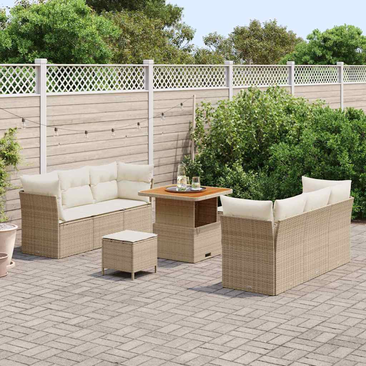 Gartenmöbel-Set aus Korbgeflecht mit beigen Kissen. Enthält ein Sofa, zwei Stühle, einen Tisch und einen kleinen Hocker auf einer Ziegelterrasse.