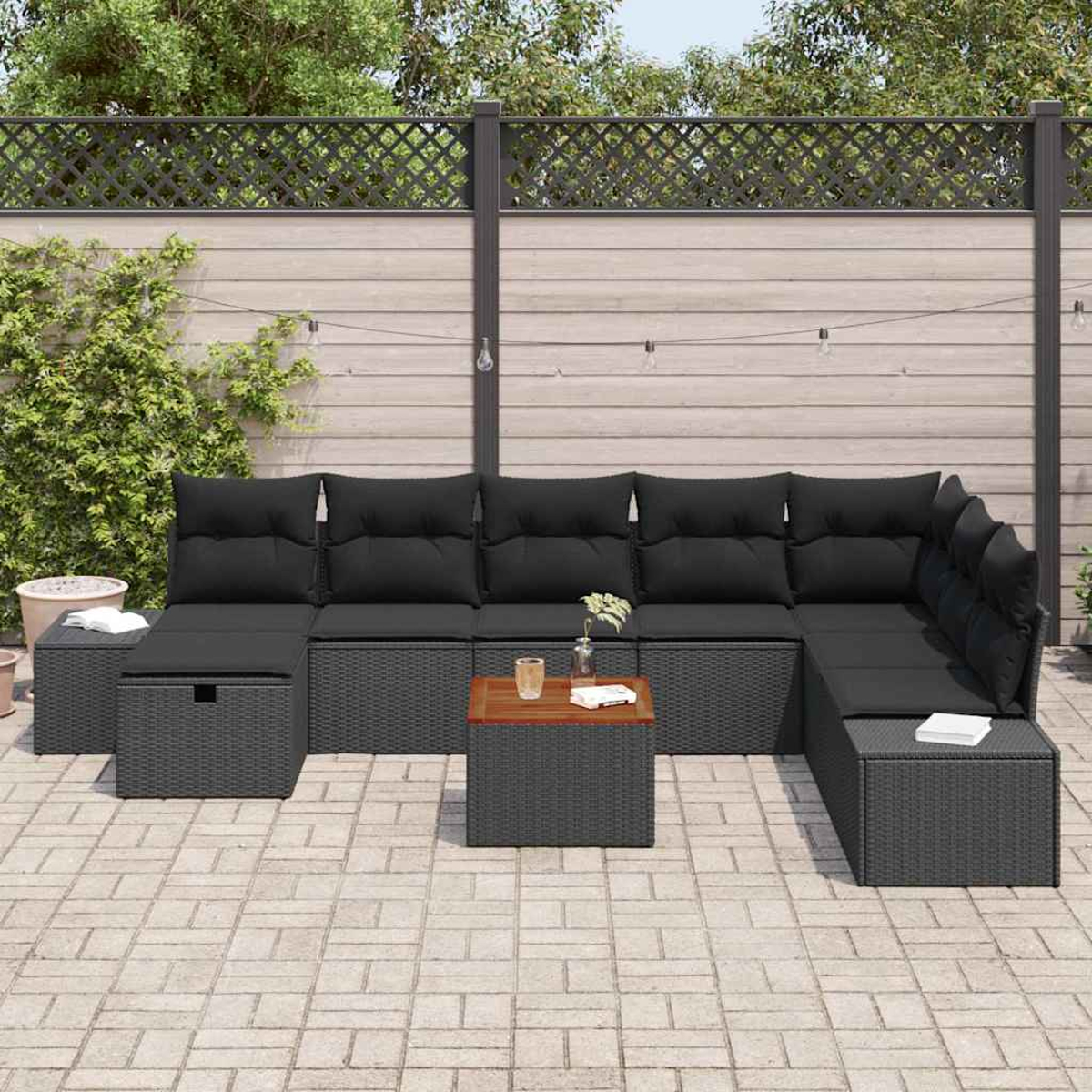 Outdoor-Ecksofa mit schwarzen Kissen und grauem Korbgeflecht. Enthält einen Holztisch und eine Backstein-Terrasse vor einem Holzzaun.