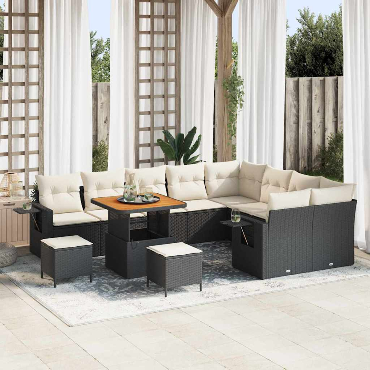 Outdoor-Ecksofa mit beigen Kissen und einem Holztisch. Zwei Hocker und ein Teppich davor. Weiße Vorhänge im Hintergrund.
