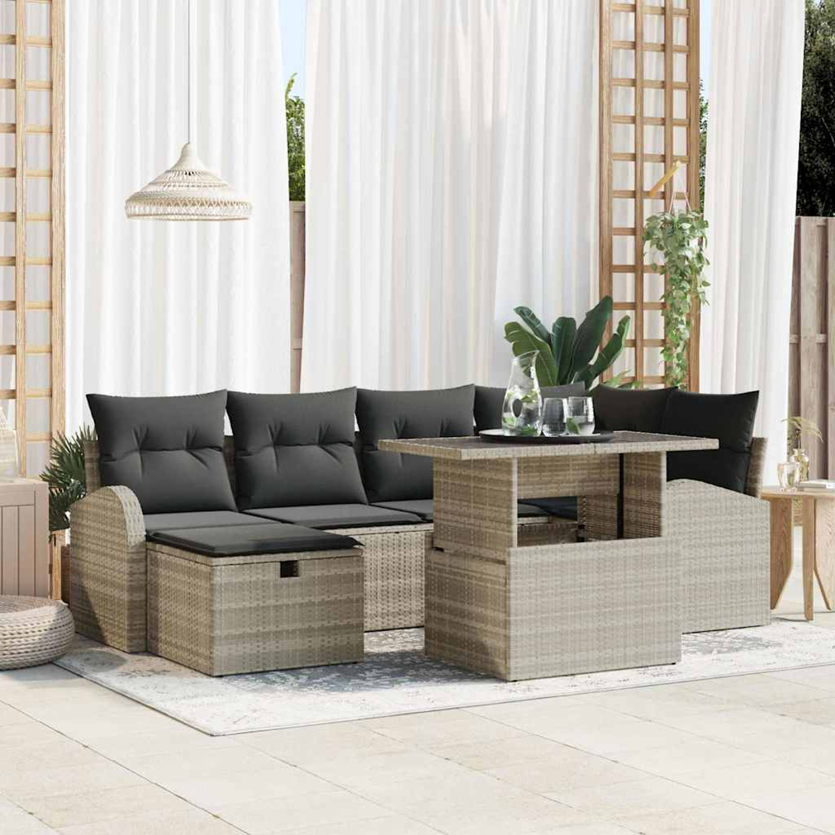 Terrassenset im Freien mit grauen Kissen, einem hellbraunen Tisch und weißen Vorhängen im Hintergrund. Eine Hängelampe ist ebenfalls sichtbar.