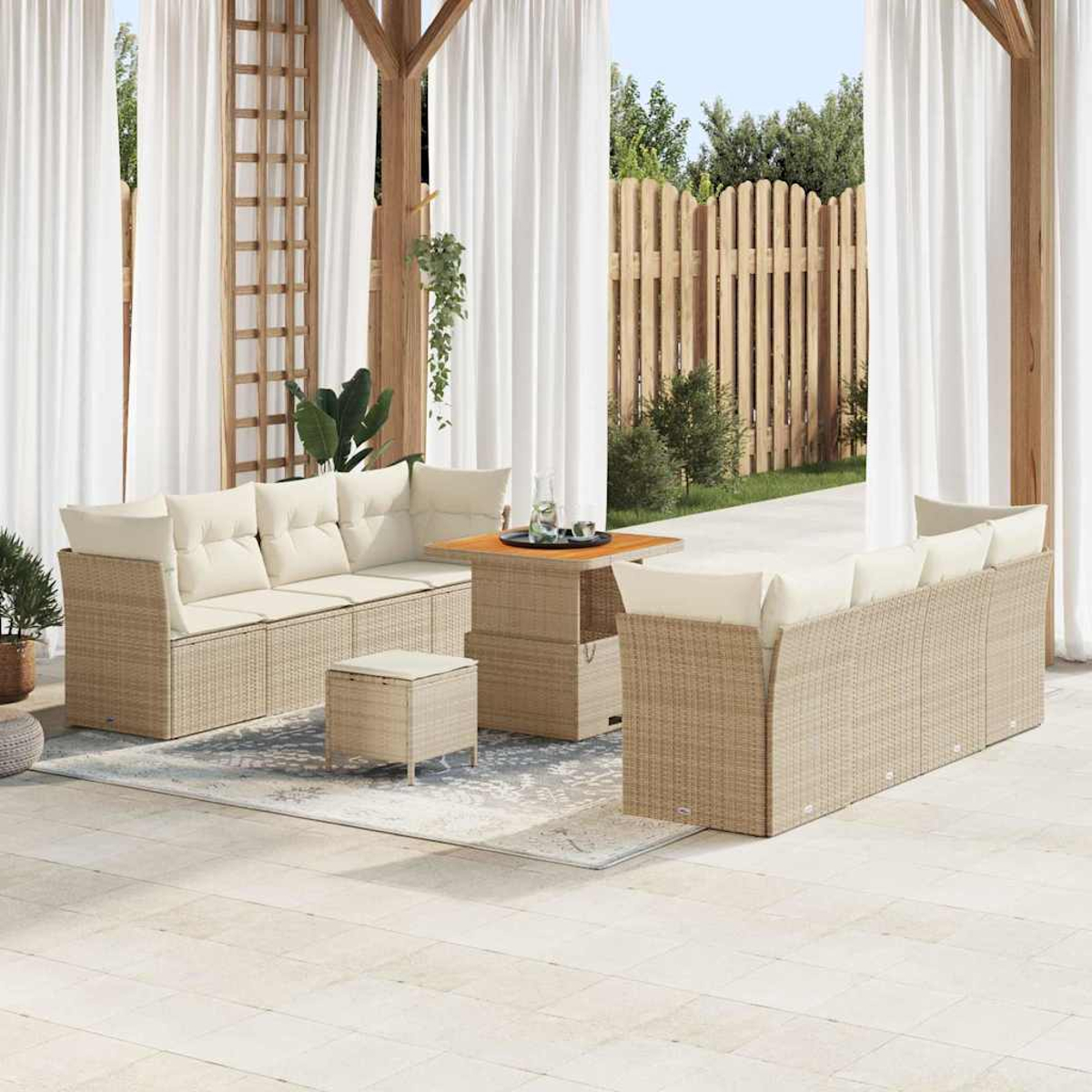 Outdoor-Sitzgruppe mit beigen Kissen. Enthält Sofa, Stühle, Tisch und Ottoman. Auf einer Terrasse mit Vorhängen und Holzzaun.
