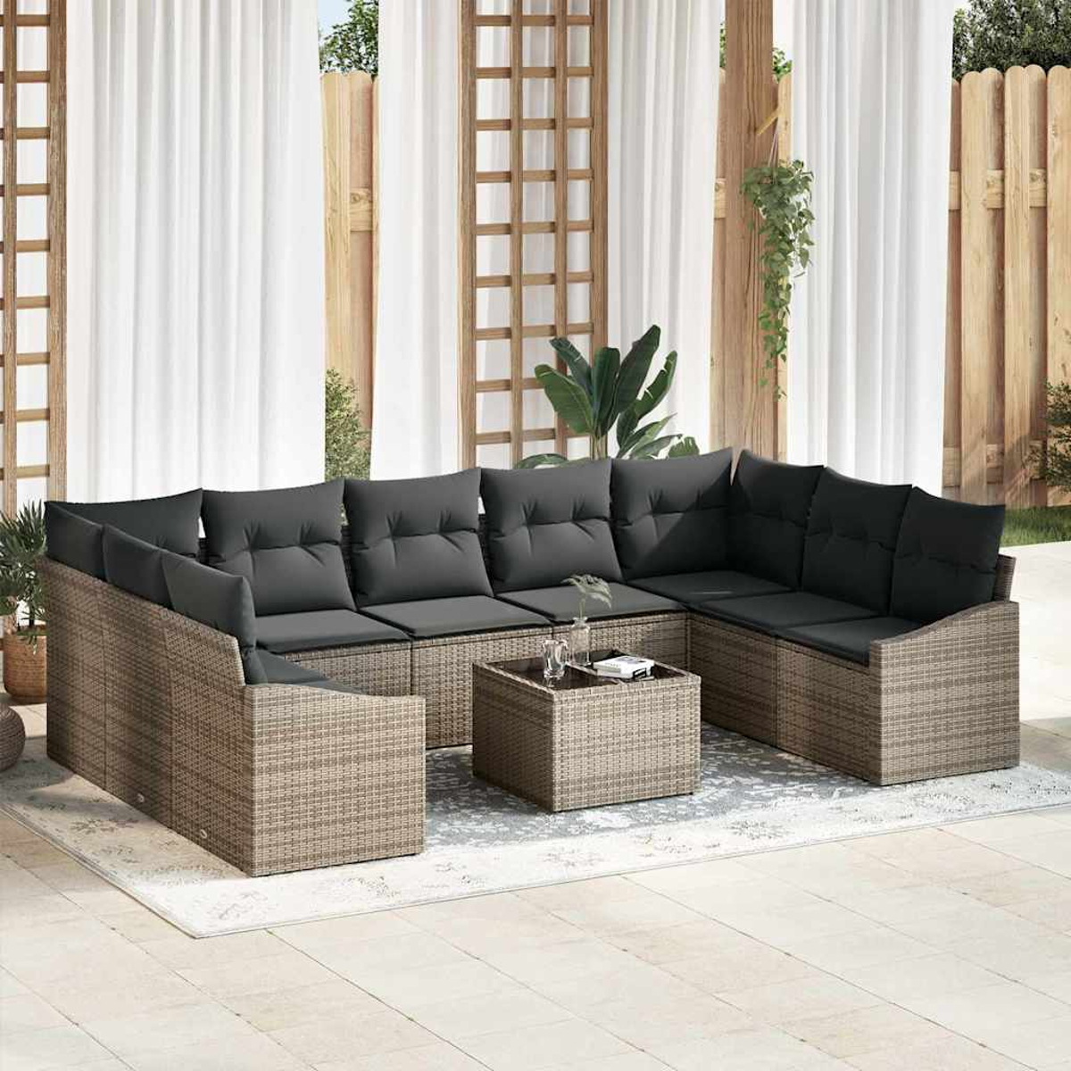 Outdoor-Ecksofa mit grauen Kissen und einem Couchtisch. Weiße Vorhänge und Holzzaun im Hintergrund.