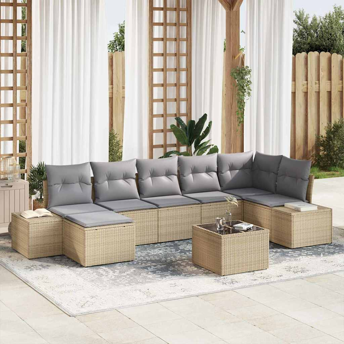 Mobiliario de patio al aire libre con cojines grises. Sofá de mimbre beige, mesa de centro y mesa auxiliar sobre una alfombra estampada. Cortinas blancas.