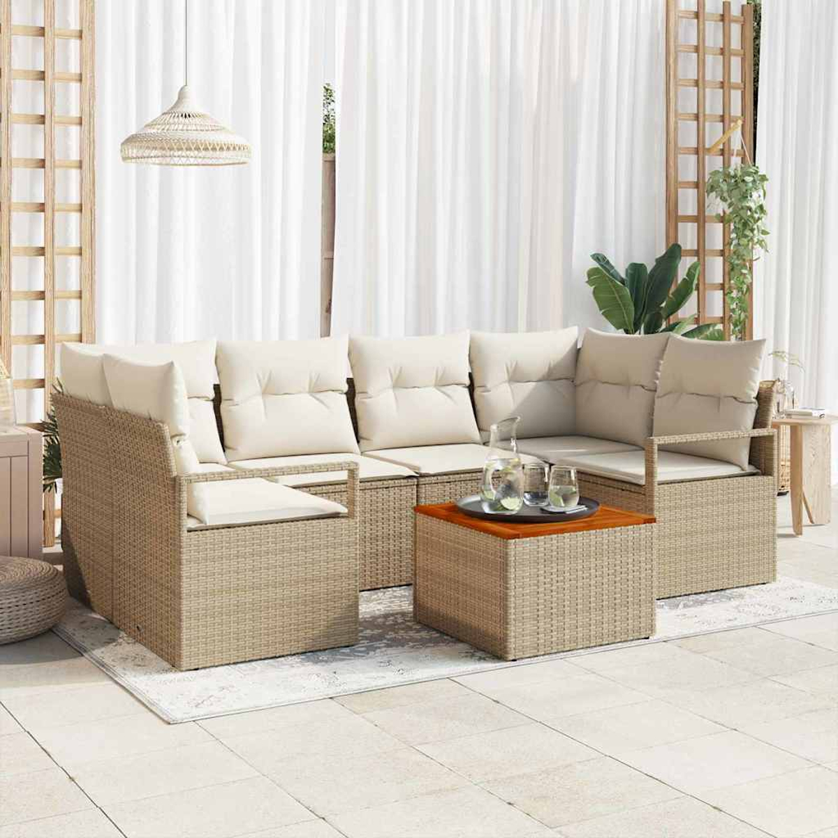 Outdoor-Rattansofa-Set mit Kissen, einem Couchtisch mit Getränken und weißen Vorhängen im Hintergrund. Eine Pendelleuchte hängt darüber.