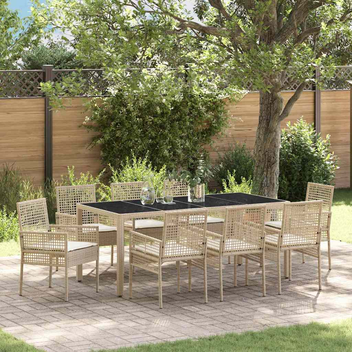 Ein Esszimmer-Set im Freien mit schwarzem Tisch und Rattanstühlen. Die Szene spielt in einem Garten mit Bäumen und einem Holzzaun.