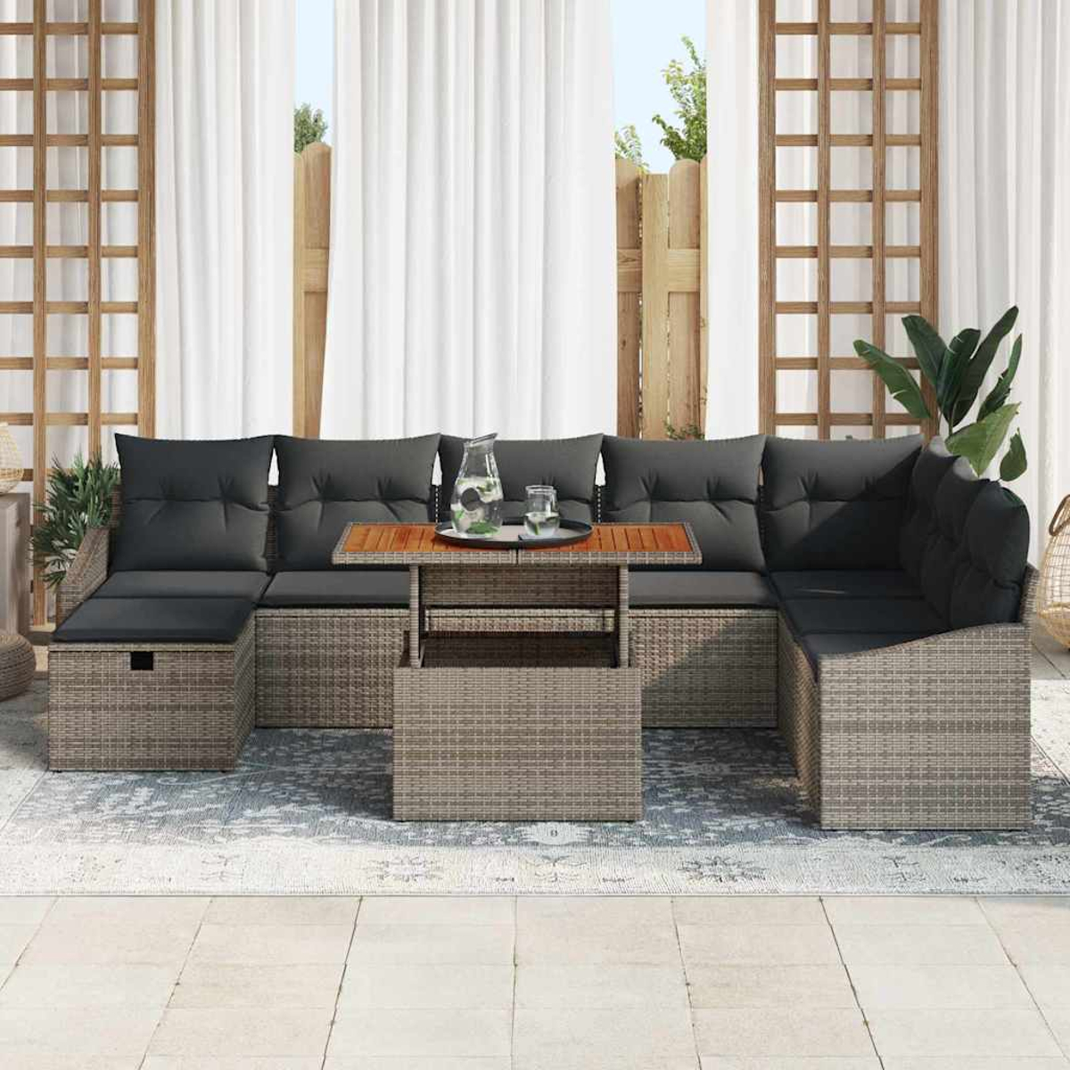 Outdoorgarnitur mit grauen Kissen und einem Holztisch, auf einem Teppich. Weiße Vorhänge und ein Holzzaun im Hintergrund.