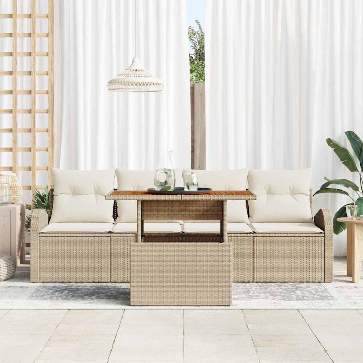 Outdoor-Set mit beigen Rattanmöbeln, einem Tisch mit Getränken, weißen Vorhängen und einer Hängelampe.