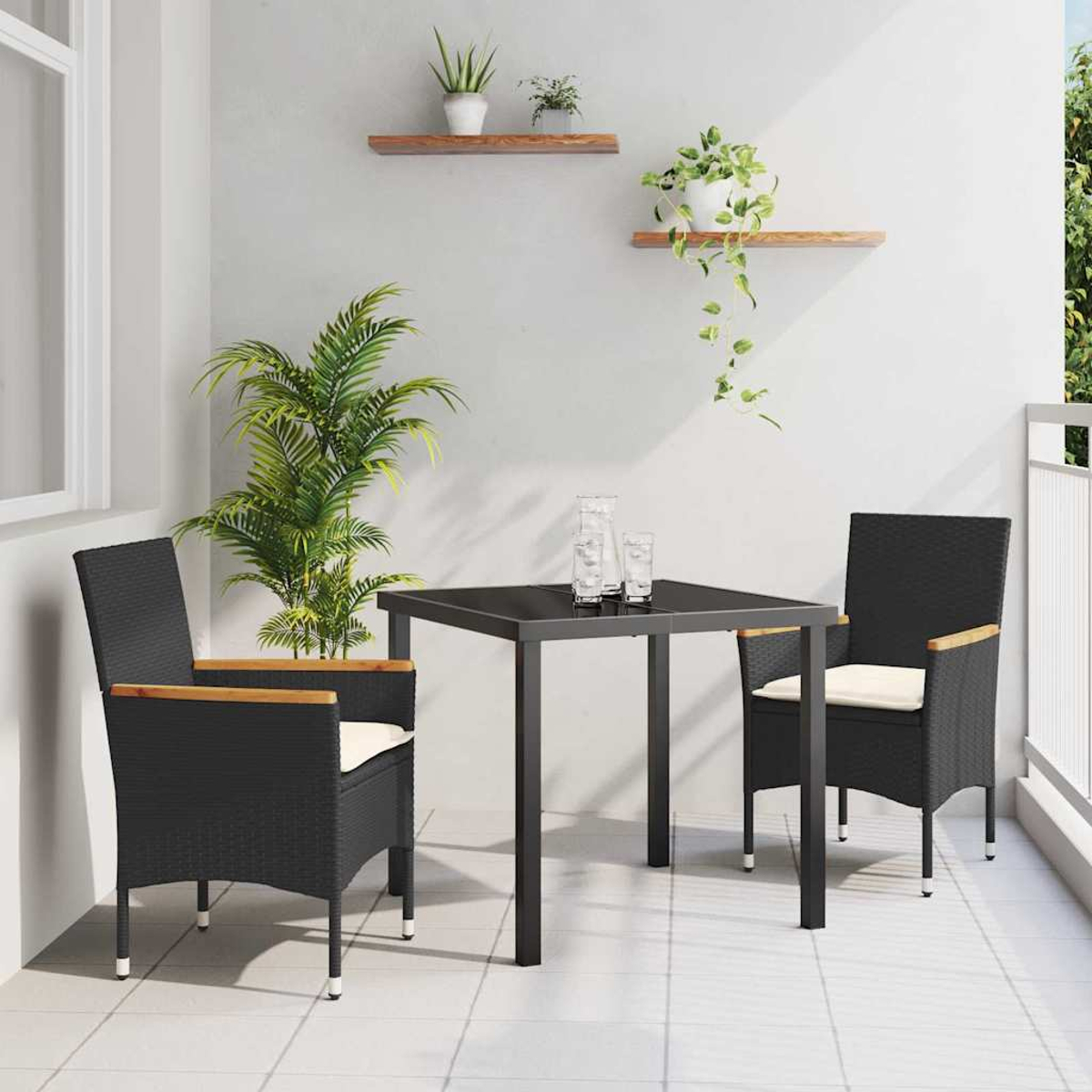 Schwarzer Tisch und Stühle auf einem Balkon mit Pflanzen. Zwei Stühle stehen dem Tisch gegenüber. Gläser stehen auf dem Tisch. Pflanzen im Hintergrund.