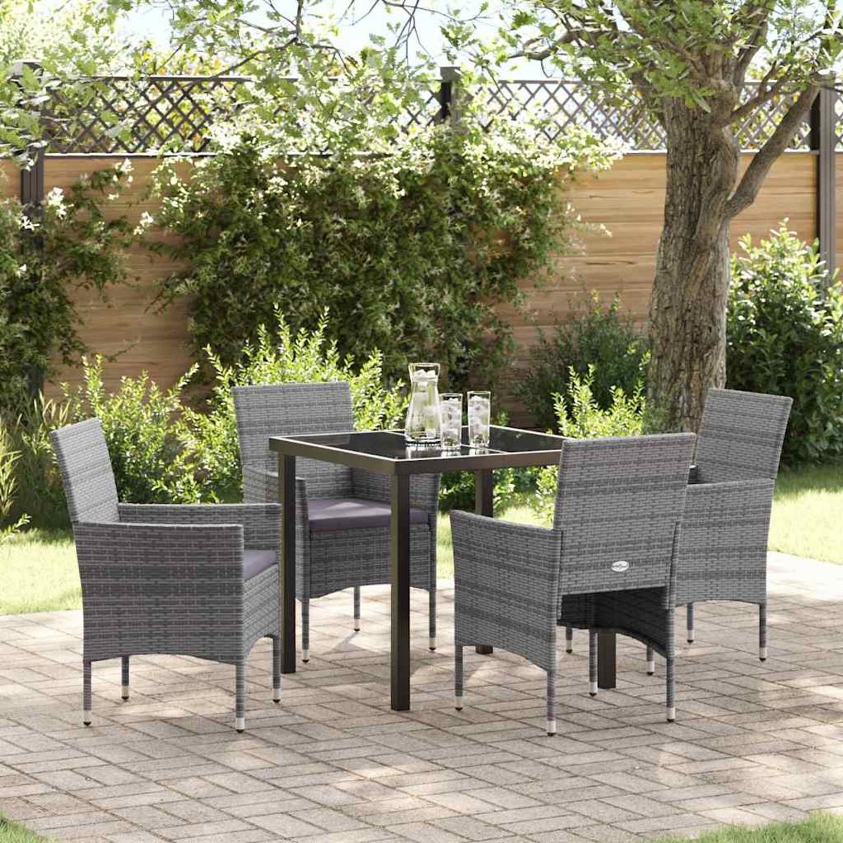 Set da patio all'aperto con tavolo quadrato, quattro sedie grigie e una caraffa con bicchieri, su pavé con sfondo verde.