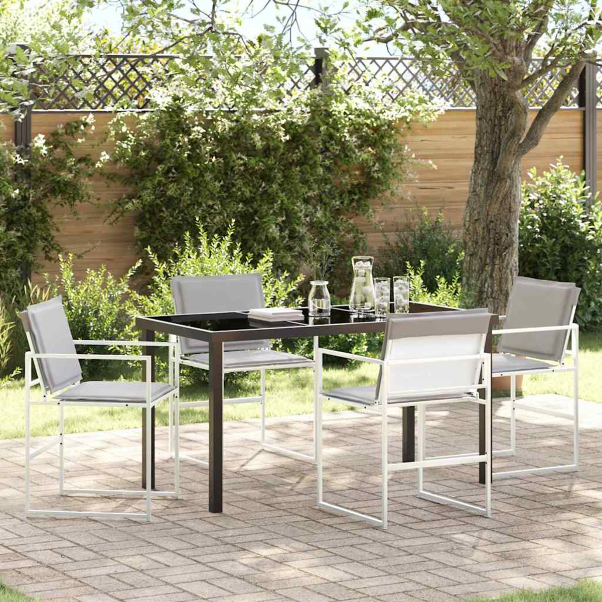 Terrassenset im Freien mit schwarzem Tisch und vier grauen Stühlen. Der Hintergrund ist ein Garten mit Bäumen und Ziegelpflaster.