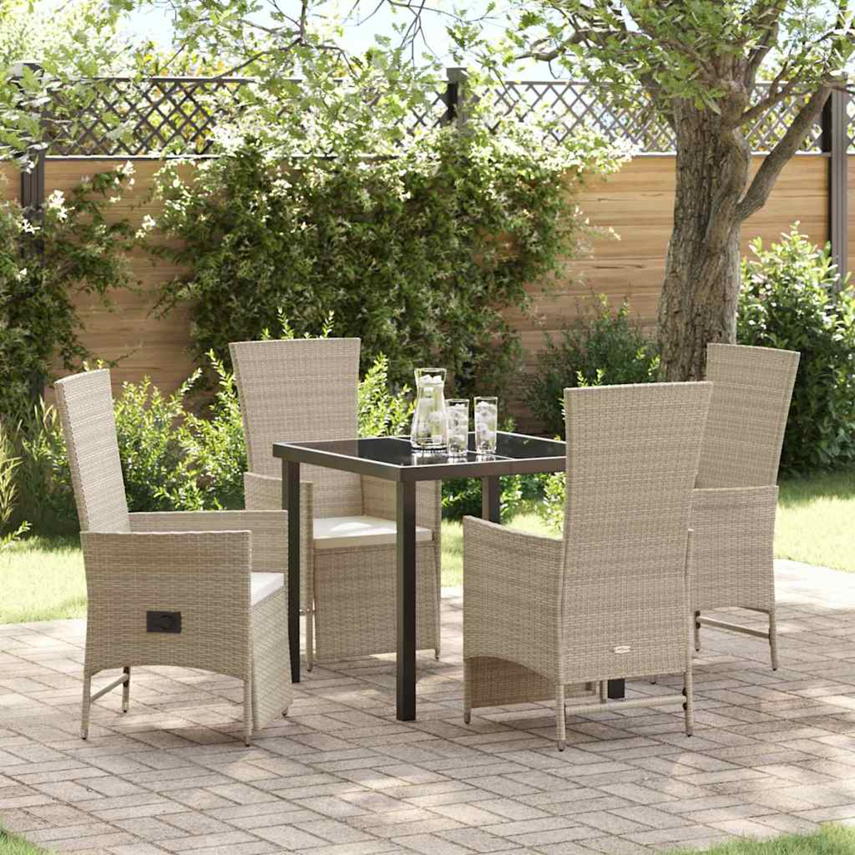 Essgruppe im Freien auf einer Terrasse. Quadratischer Tisch mit vier Stühlen. Krug und Gläser auf dem Tisch. Grünes Laub und Baum im Hintergrund.