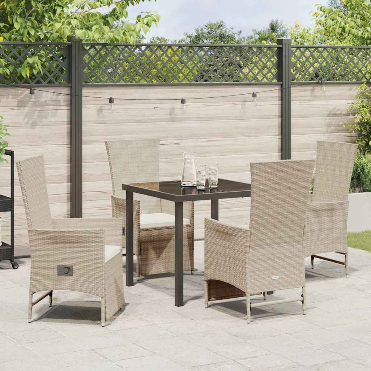 Gartenset mit quadratischem Tisch, vier beigen Korbstühlen und dekorativem Zaun im Hintergrund.
