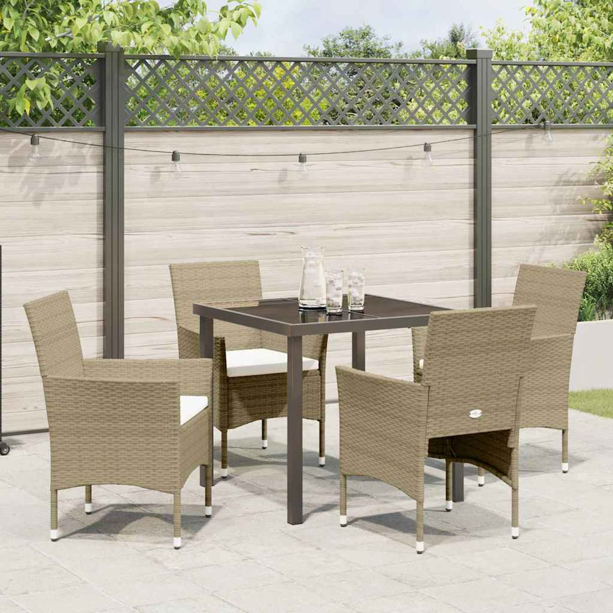 Set da patio: tavolo, quattro sedie e una recinzione. Il tavolo ha un piano in vetro, le sedie sono intrecciate. Sfondo con vegetazione e una ghirlanda.