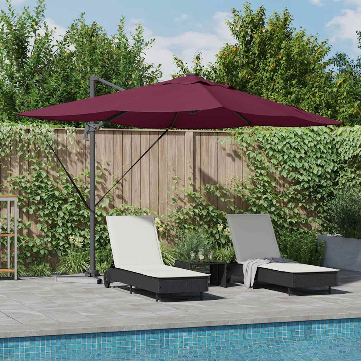 Eine Terrasse mit einem weinroten Sonnenschirm, zwei Liegestühlen, einem kleinen Tisch und einem Pool. Ein Holzzaun im Hintergrund.