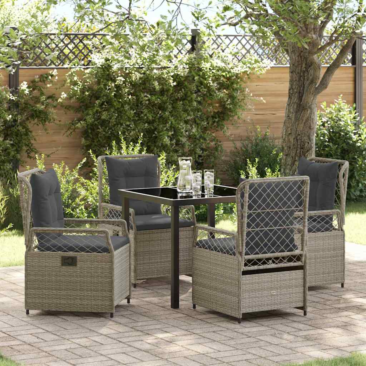 Terrassenset: vier Stühle mit grauen Kissen um einen schwarzen Tisch mit Getränken. Im Hintergrund grüne Pflanzen und ein Holzzaun.