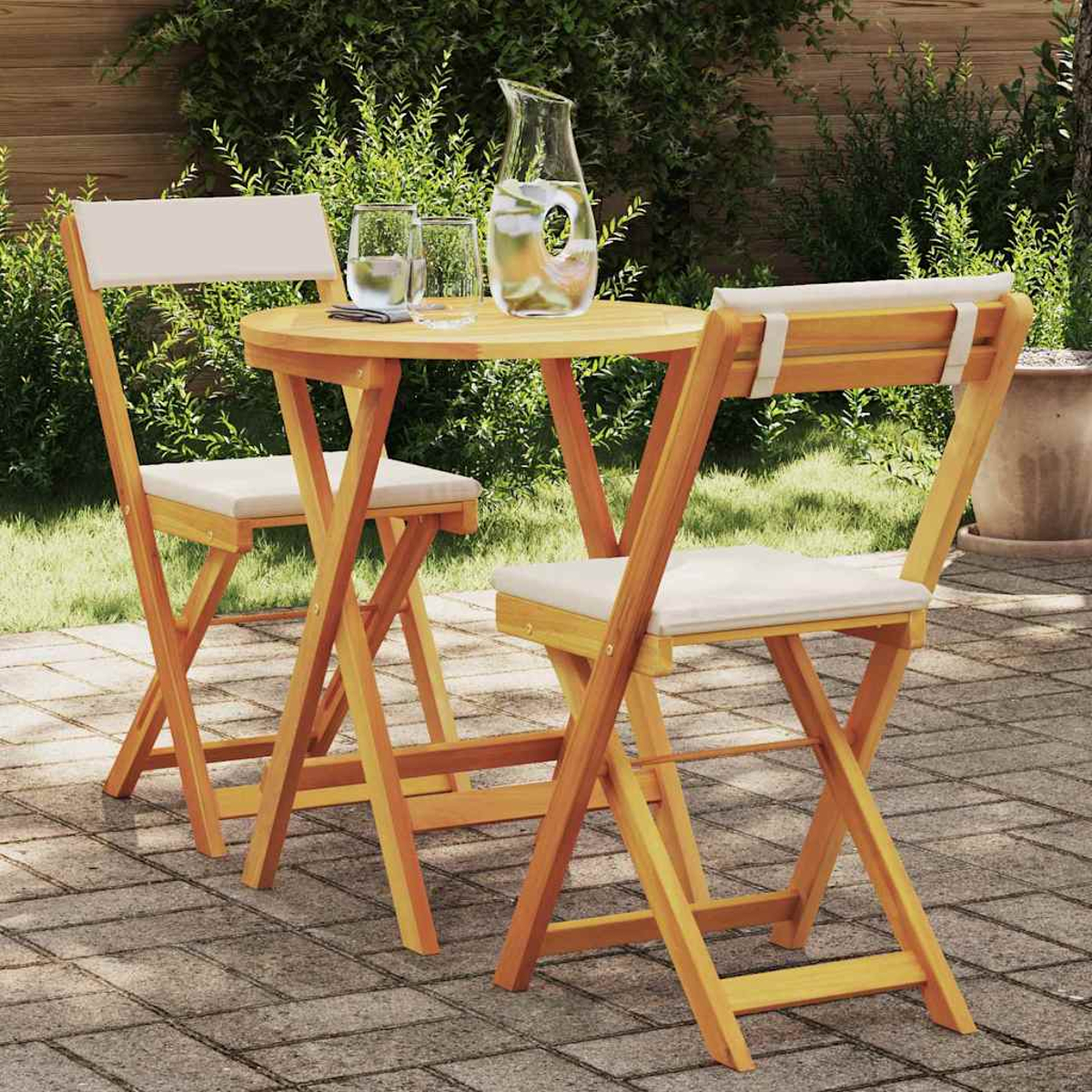 Mesa de madera y dos sillas en el patio. Una jarra de agua y vasos sobre la mesa. Arbustos verdes en el fondo.