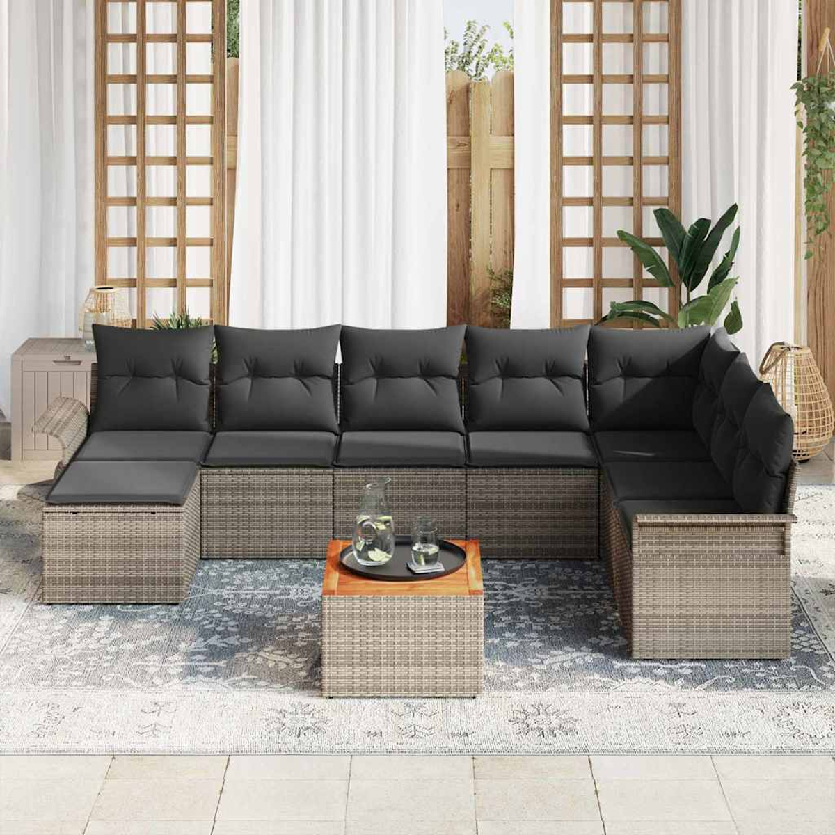 Outdoor-Ecksofa mit grauen Kissen. Ein kleiner Tisch mit Tablett und Glas Wasser. Hintergrund: Fenster und Vorhänge.