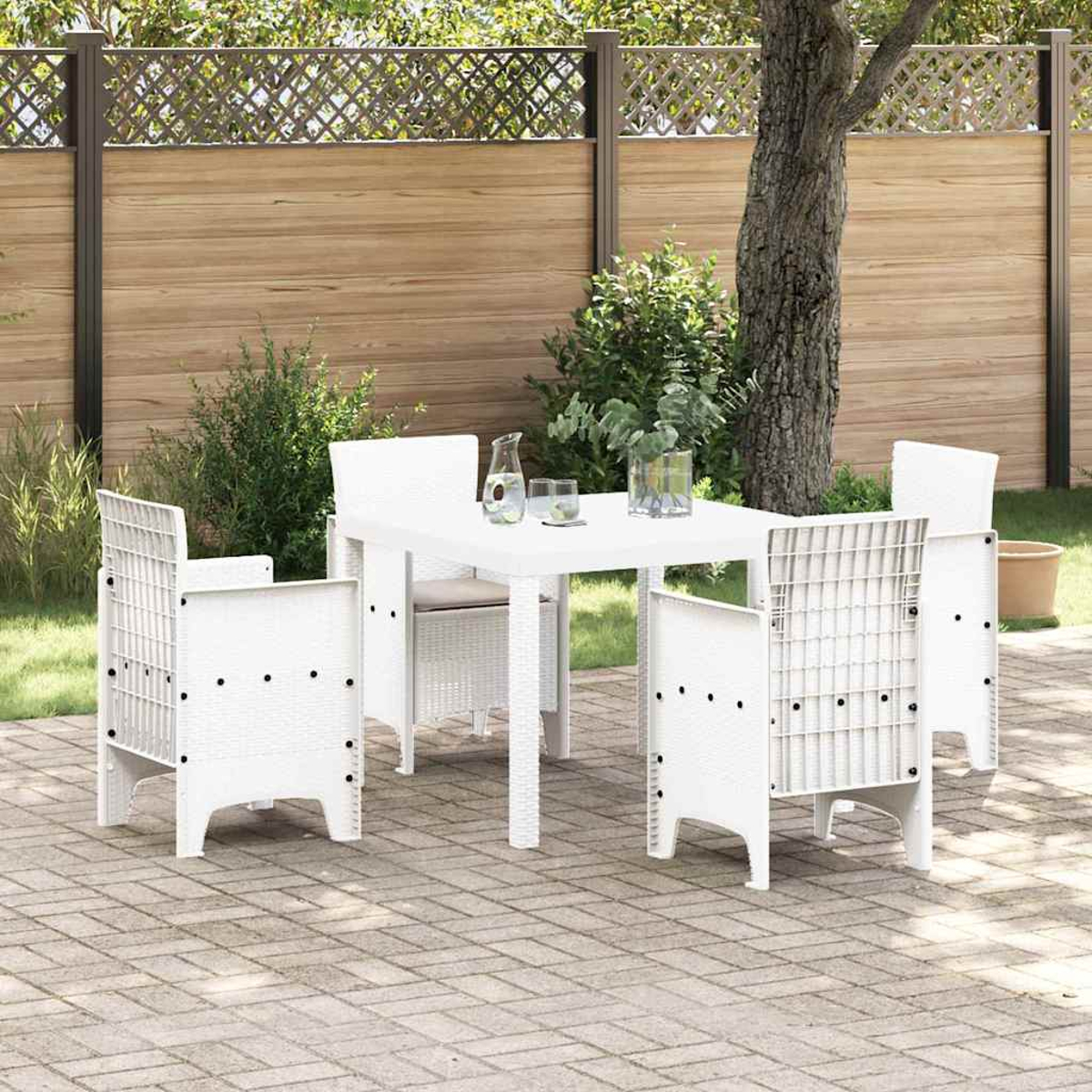 Weißes Ess-Set im Freien: Tisch und Stühle. Hintergrund: Holzzaun, Grünpflanzen und Baum, für eine Terrassen-Szene.