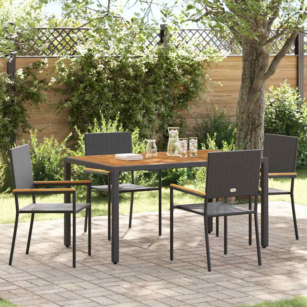 Essgruppe im Freien mit Tisch, Stühlen und Getränken auf einer Terrasse. Grünes Laub und Bäume im Hintergrund, sonniger Tag.