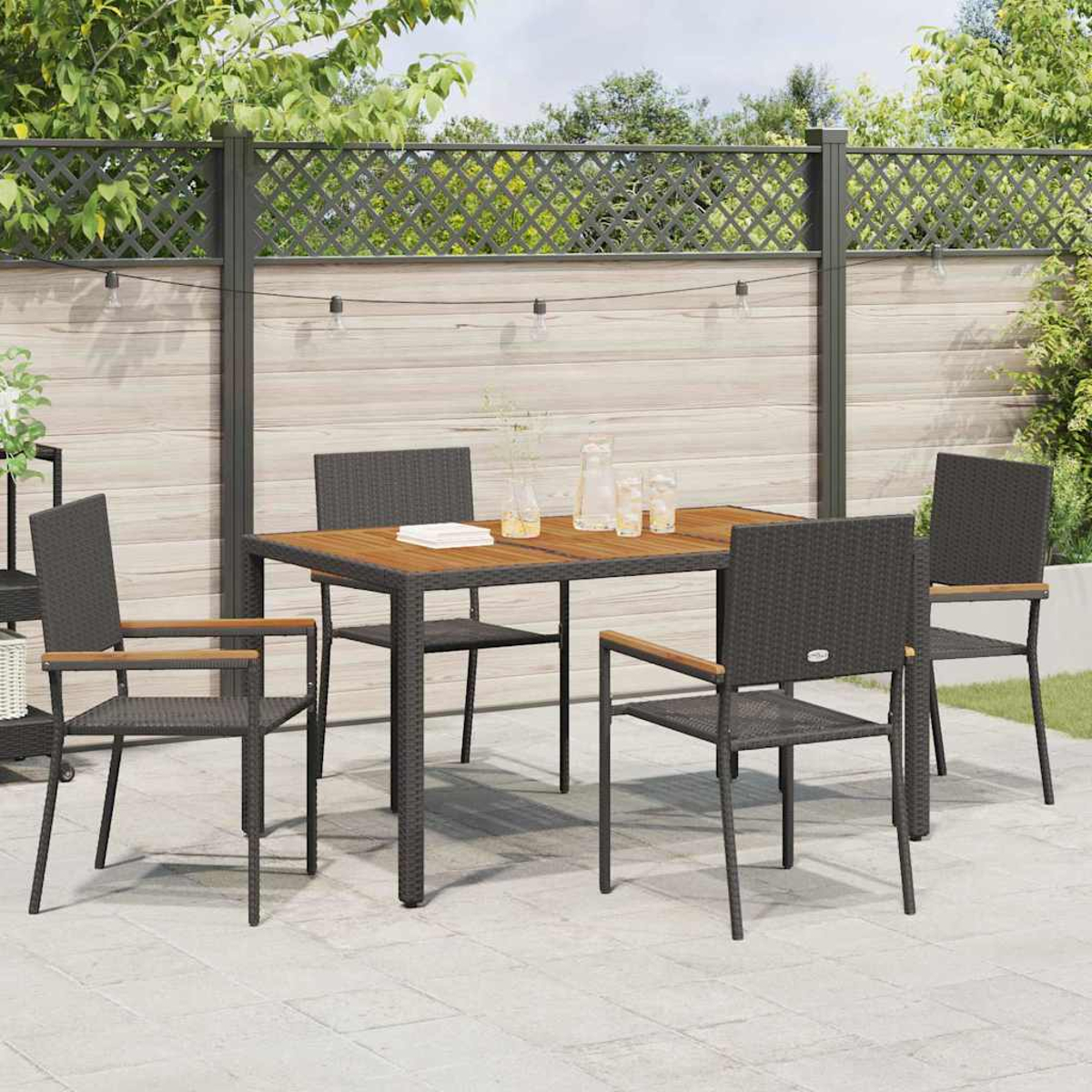 Essgruppe im Freien mit Tisch, Stühlen und Zubehör. Auf einer Terrasse mit Holzzaun und Grün im Hintergrund.