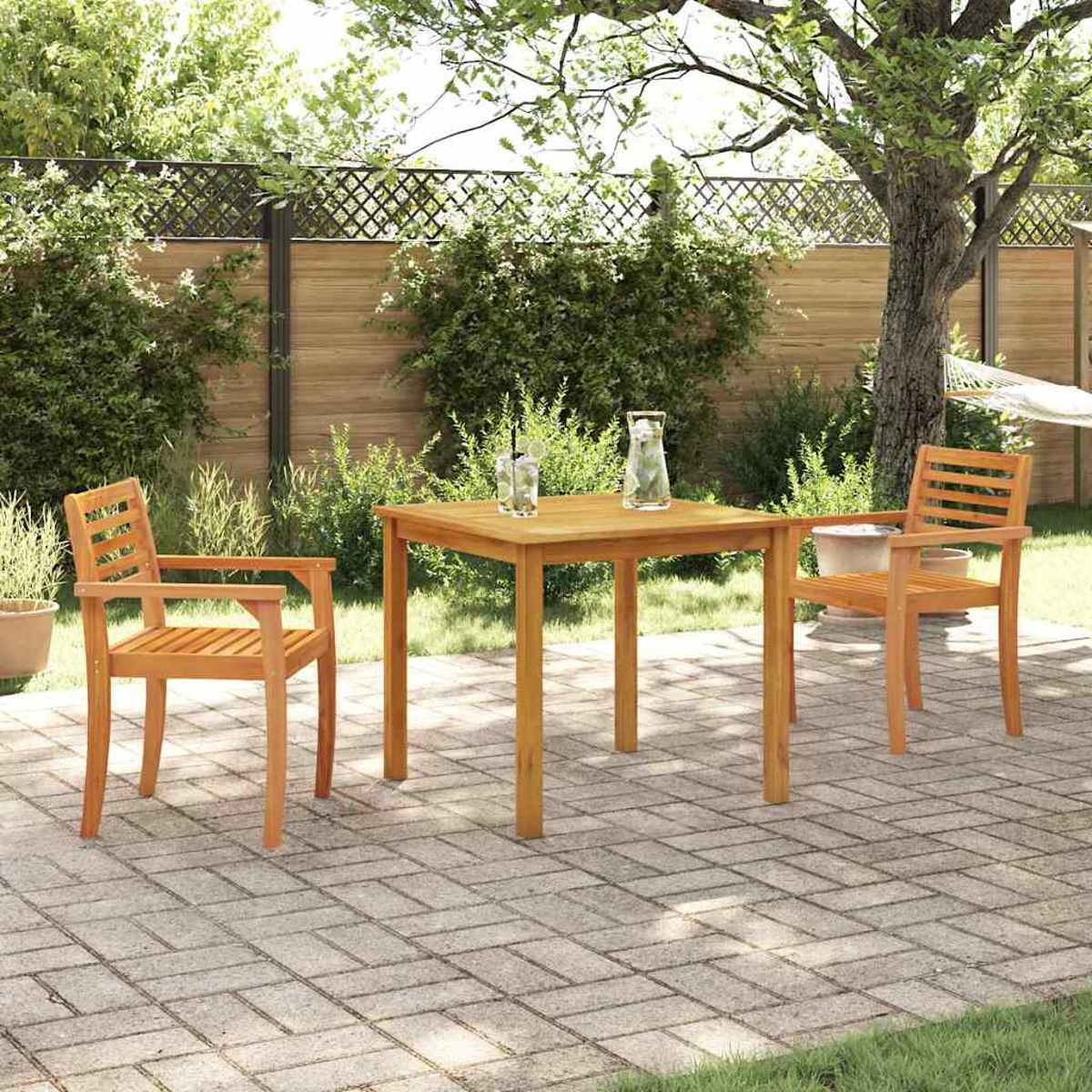 Ein Holztisch und Stühle auf einer Ziegelterrasse. Im Hintergrund befinden sich ein Baum, ein Zaun und Pflanzen. Getränke stehen auf dem Tisch.