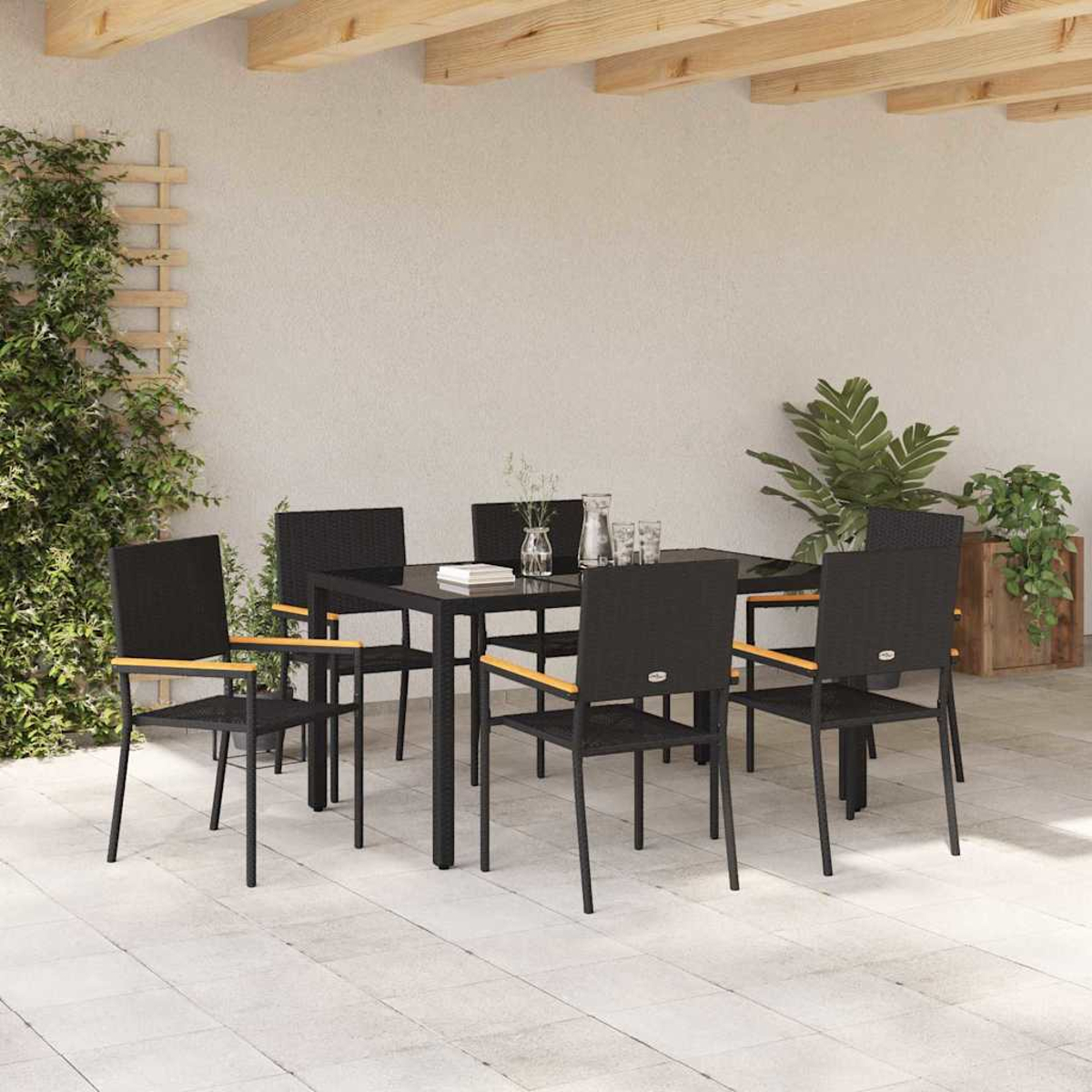 Essgruppe im Freien mit schwarzen Stühlen und Tisch. Pflanzen und Spalier an der Wand. Holzbalken oben. Fliesenboden.