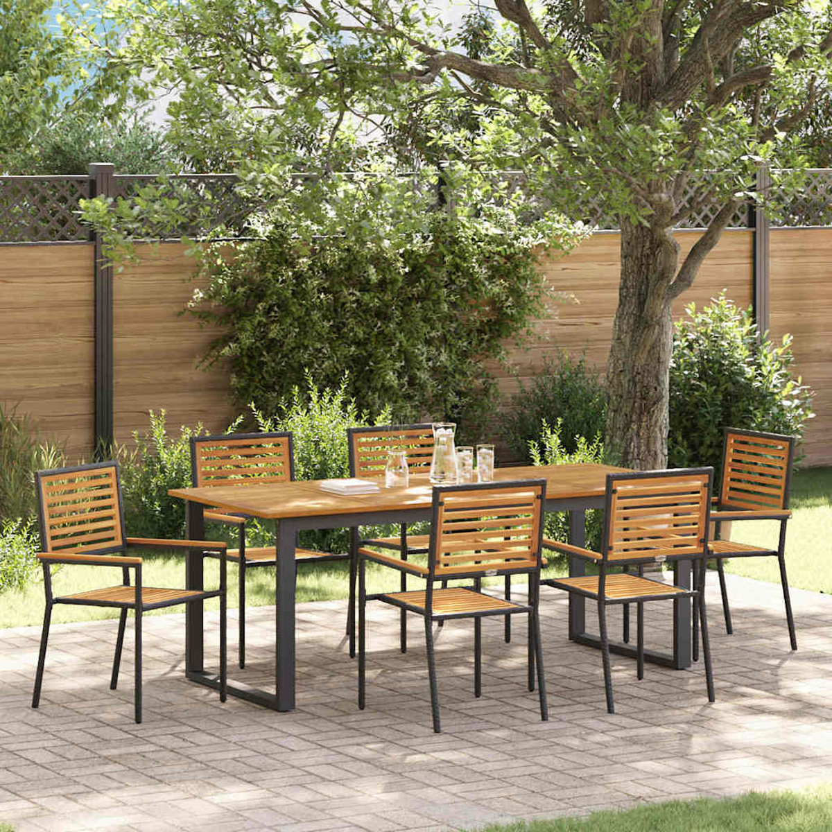 Ein Holztisch und Stühle in einem Garten. Auf dem Tisch stehen eine Glaskanne und Gläser. Der Hintergrund ist grün.