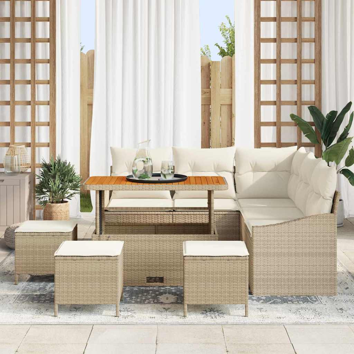 Rattan-Sofa-Set für den Außenbereich mit Kissen, Tisch und Hockern. Enthält Pflanzen, Wasserkrug und weiße Vorhänge im Hintergrund.