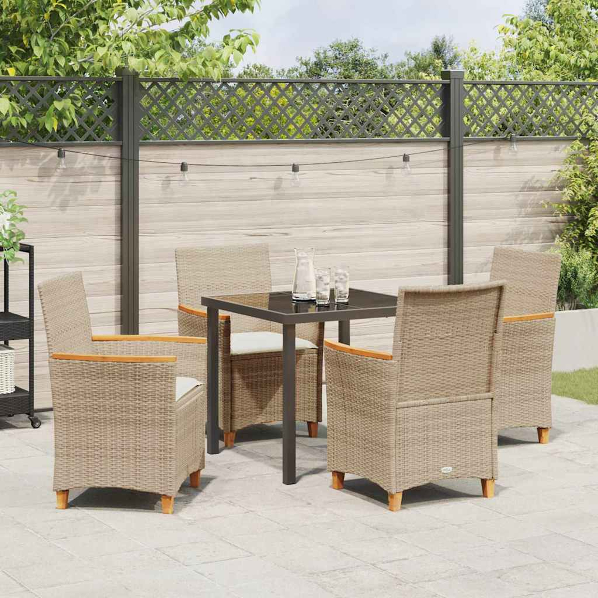 Essgruppe im Freien auf einer Terrasse. Sie umfasst einen quadratischen Tisch, vier Stühle und einen dekorativen Zaun im Hintergrund.