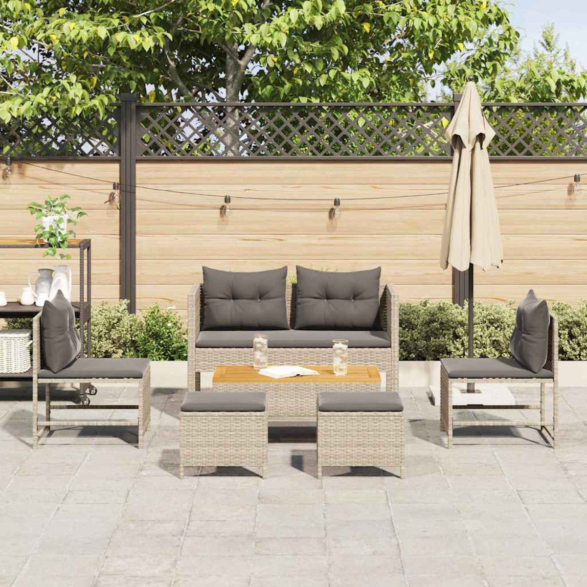 Gartenmöbel-Set mit Sofa, zwei Stühlen, zwei Hockern und einem Tisch. Ein beiger Sonnenschirm steht im Hintergrund.