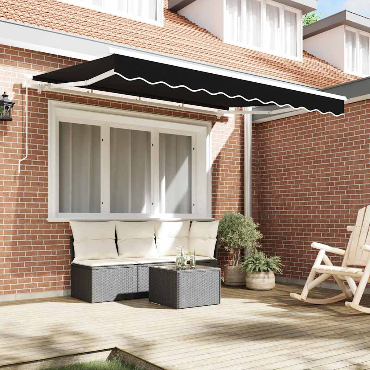 Un toldo negro se extiende sobre un patio con una zona de estar, mesa y plantas. Una mecedora se encuentra cerca contra una pared de ladrillo.