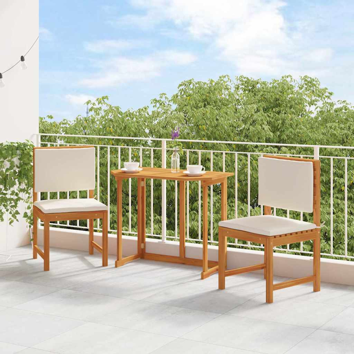 Ein Balkon mit Holztisch und zwei Stühlen. Baumreicher Hintergrund und blauer Himmel. Tassen und eine Blumenvase auf dem Tisch.