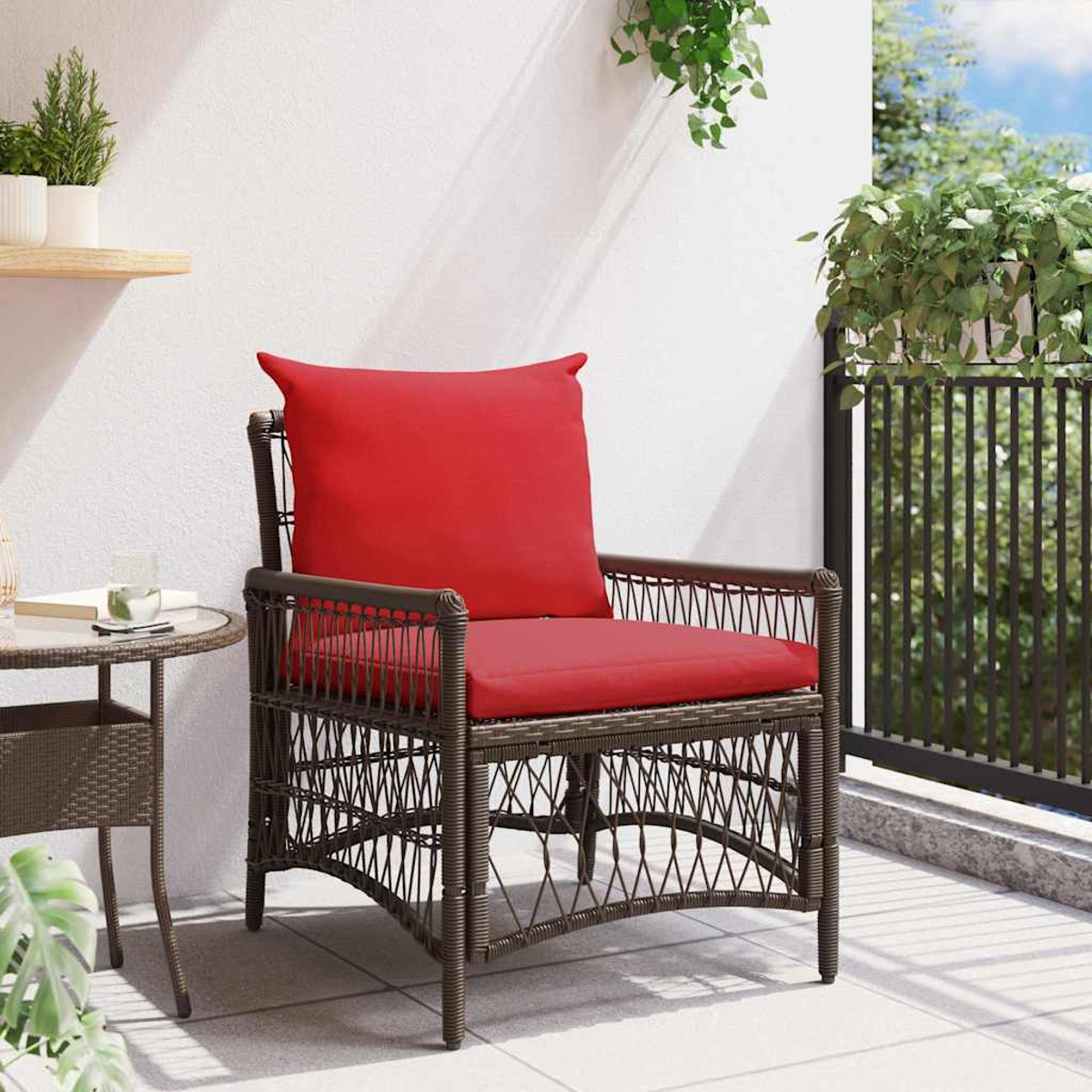 Ein brauner Korbstuhl mit rotem Kissen steht auf einer Terrasse. Ein kleiner Tisch und Pflanzen sind ebenfalls vorhanden.