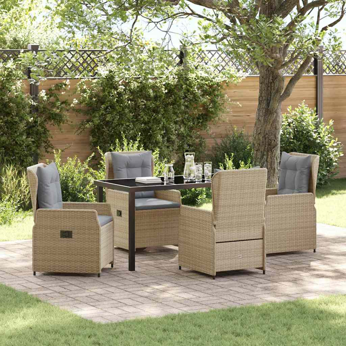 Terrassenset mit vier Korbstühlen um einen Tisch, graue Kissen. Bäume und Zaun im Hintergrund.