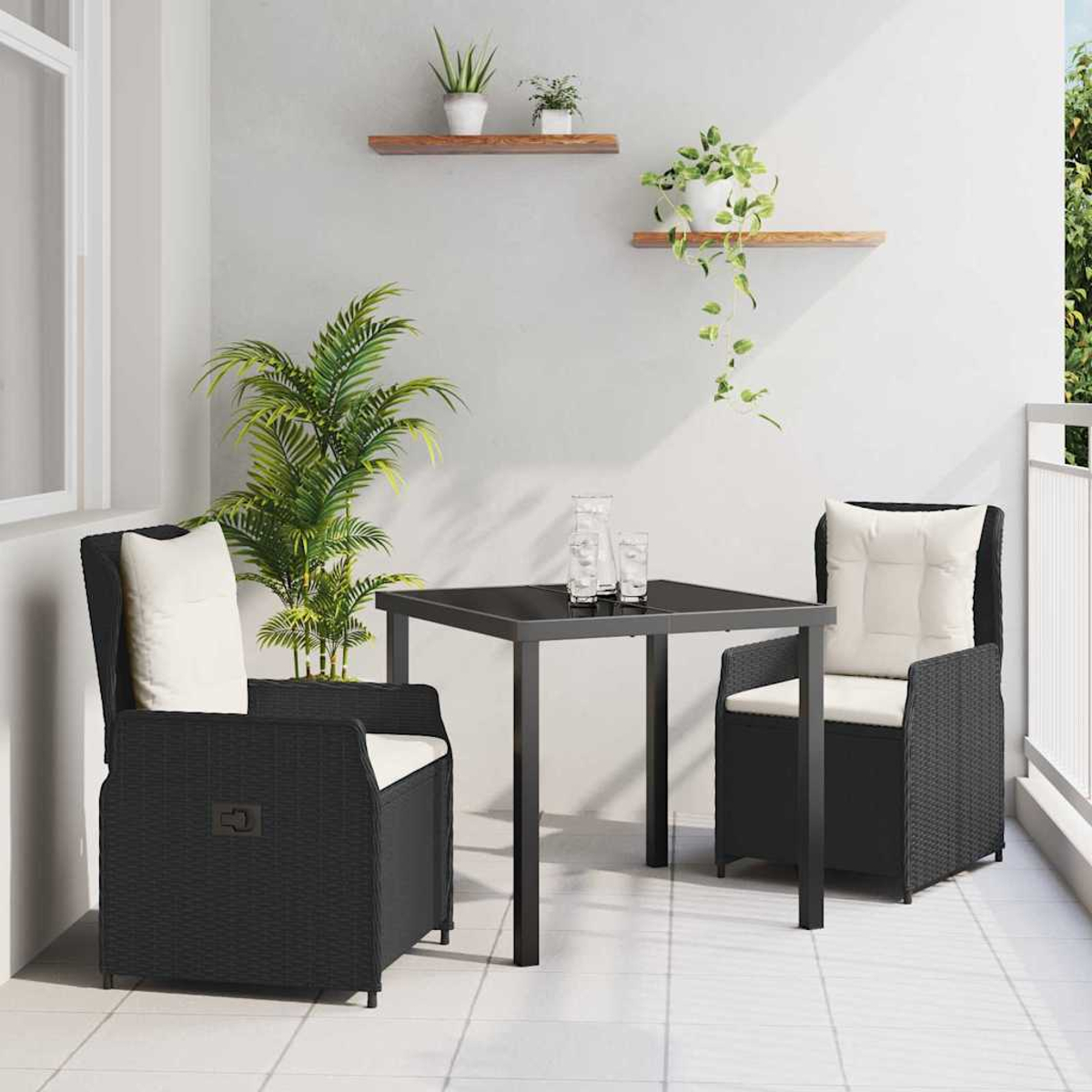 Schwarzes Terrassenset mit zwei Stühlen, einem Tisch und Kissen. Pflanzen in Töpfen auf Regalen und eine große Pflanze im Hintergrund.