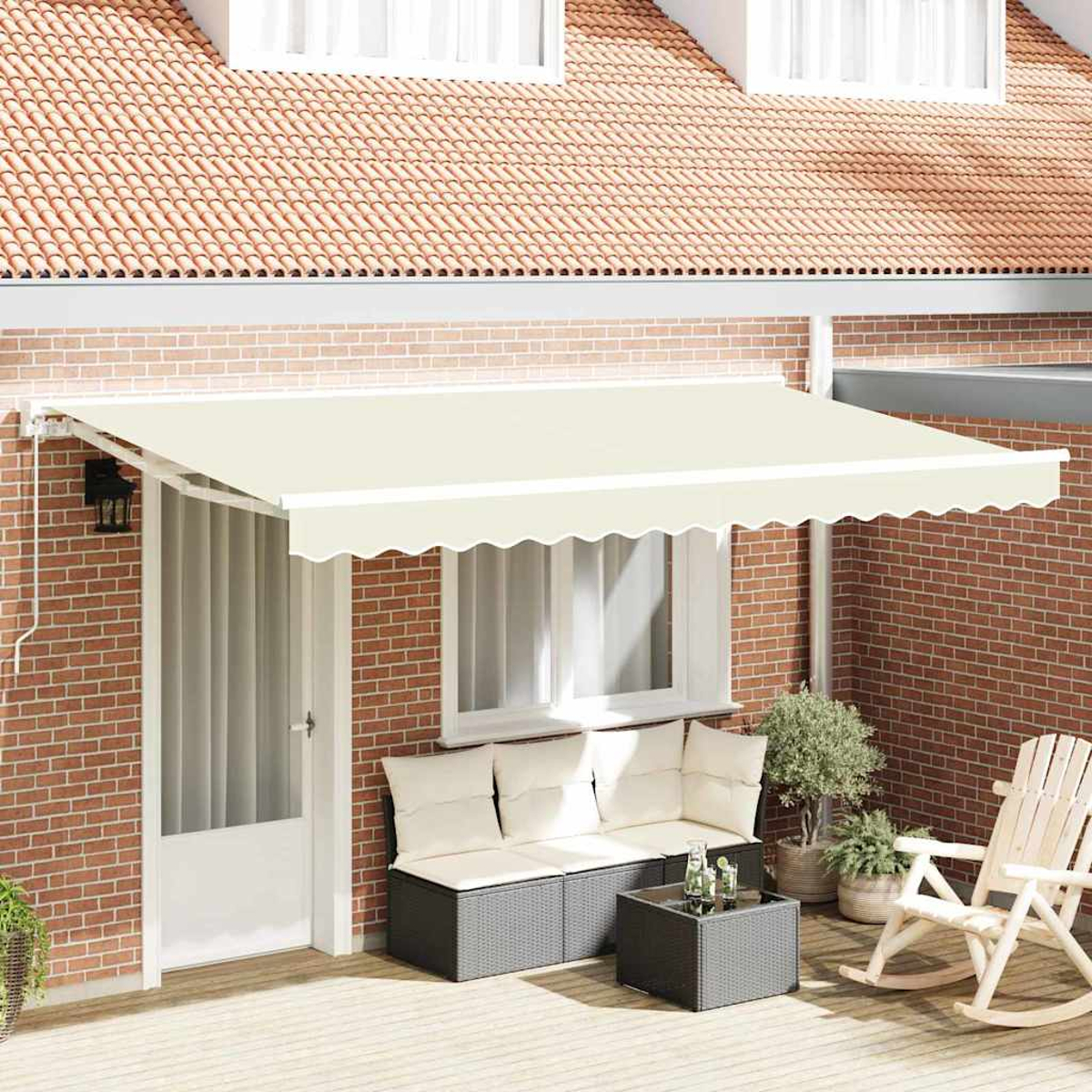 Eine beige Markise bedeckt eine Terrasse mit Sofa, Tisch und Schaukelstuhl. Rote Backsteinmauer und Ziegeldach im Hintergrund.