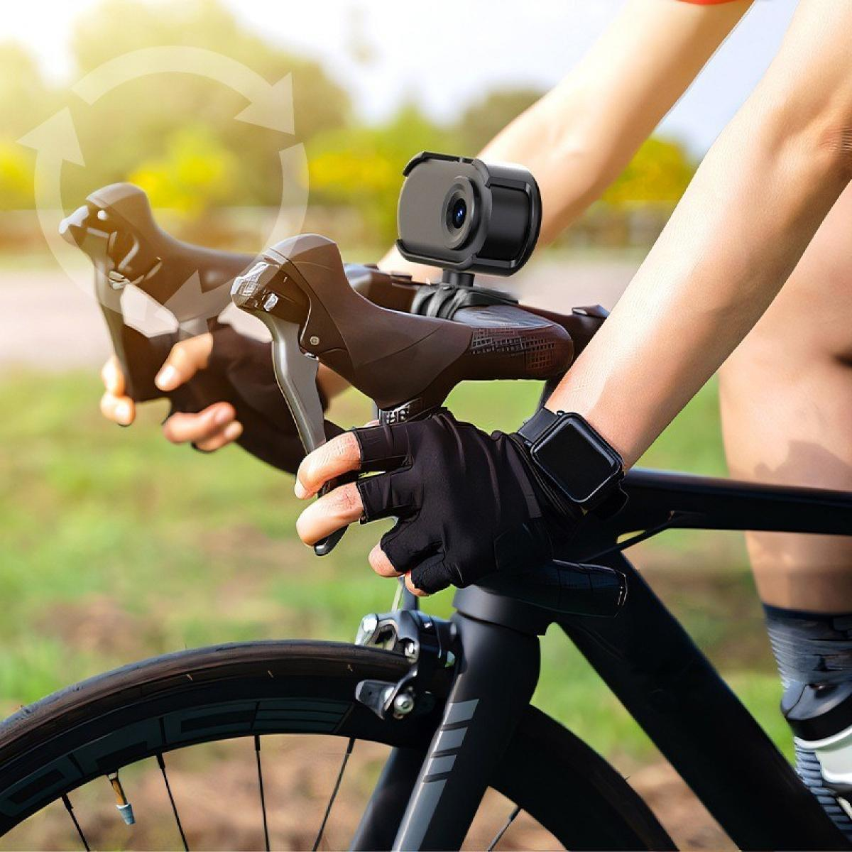 Radfahrer fährt mit einem schwarzen Fahrrad mit Kamera am Lenker. Er trägt schwarze Handschuhe und eine Smartwatch. Grünes Gras im Hintergrund.
