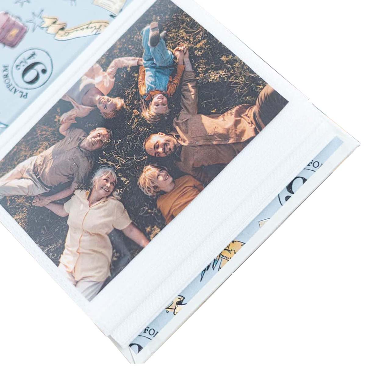 Une famille est allongée sur l'herbe, souriante. Un album photo est montré. La photo représente six personnes. L'album a une couverture bleue.