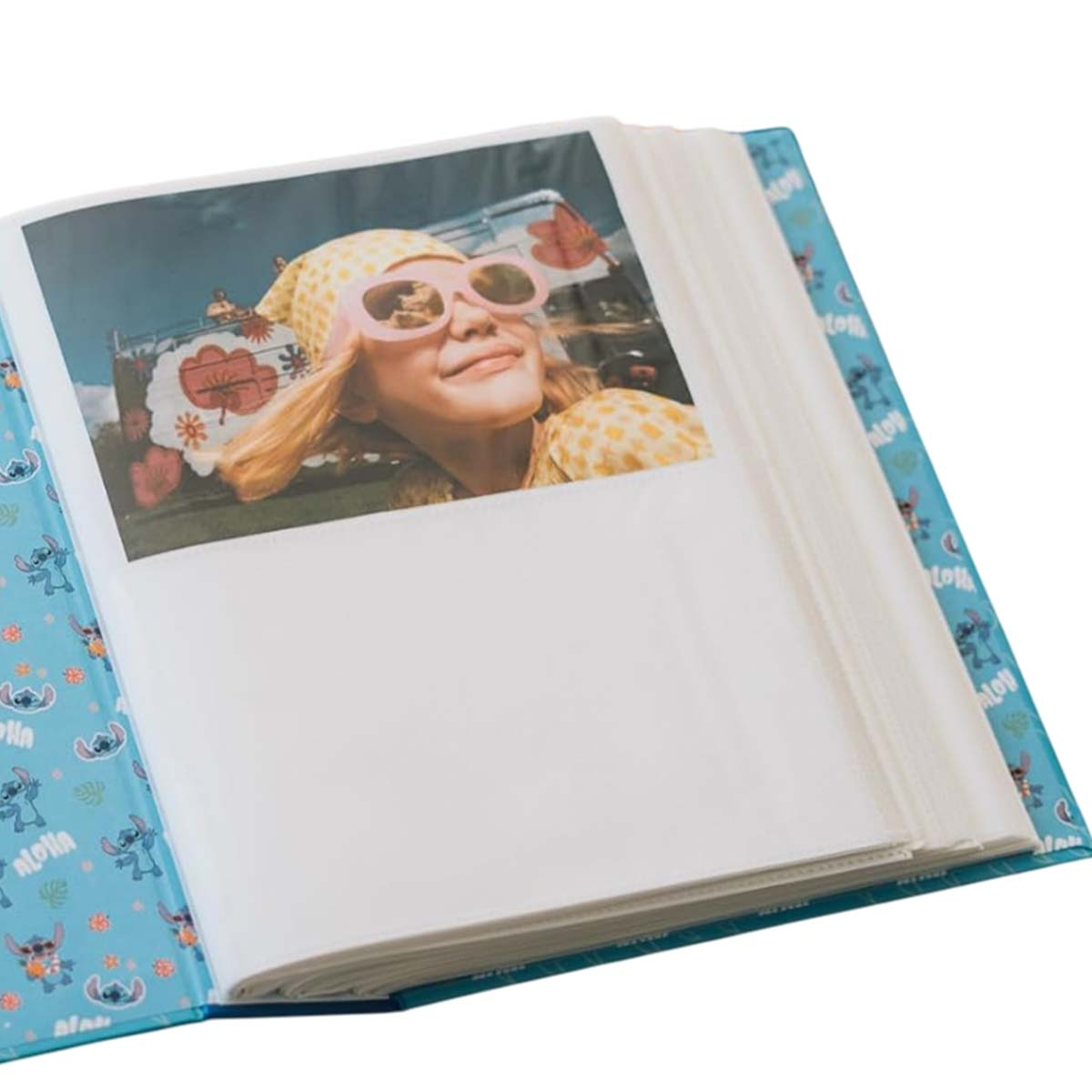 Ein offenes Fotoalbum mit einem Bild einer Frau mit Sonnenbrille und einem Van im Hintergrund. Album ist blau mit Stitch-Designs.