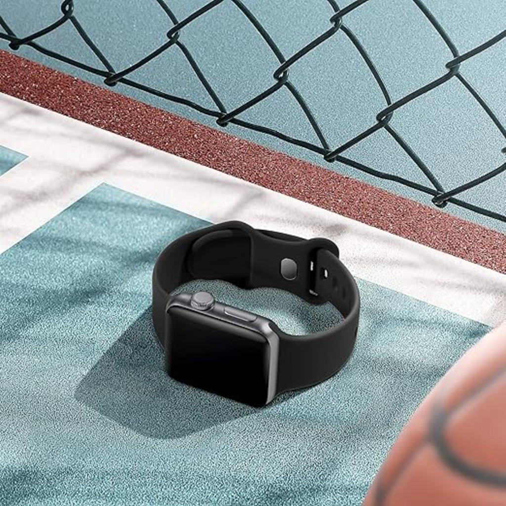 Eine schwarze Smartwatch liegt auf einer strukturierten Oberfläche. Der Hintergrund zeigt einen Basketballplatz, einen Zaun und einen Ball.