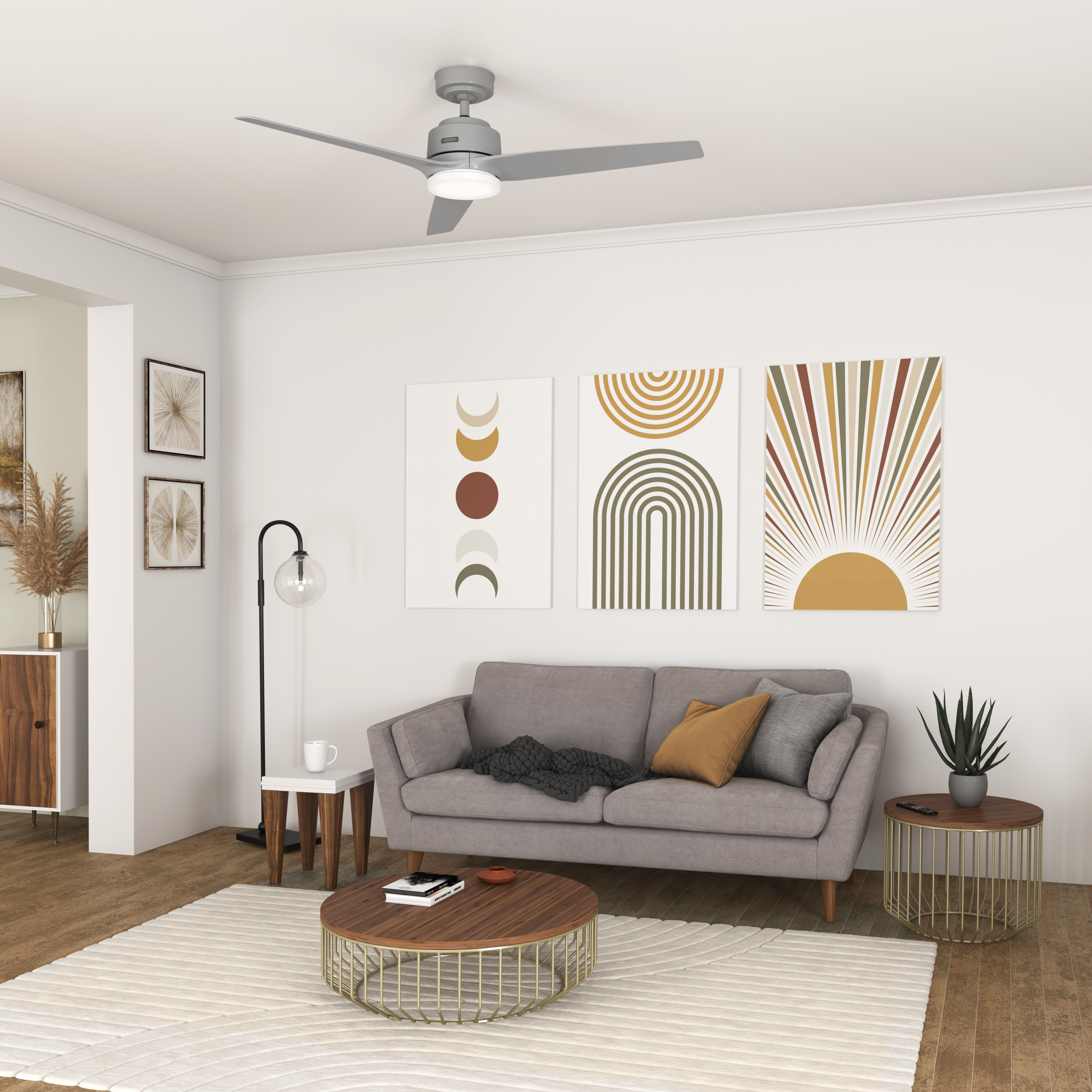Wohnzimmer mit grauem Sofa, Kunst, Teppich und Deckenventilator. Ein Couchtisch und ein Beistelltisch sind ebenfalls vorhanden.