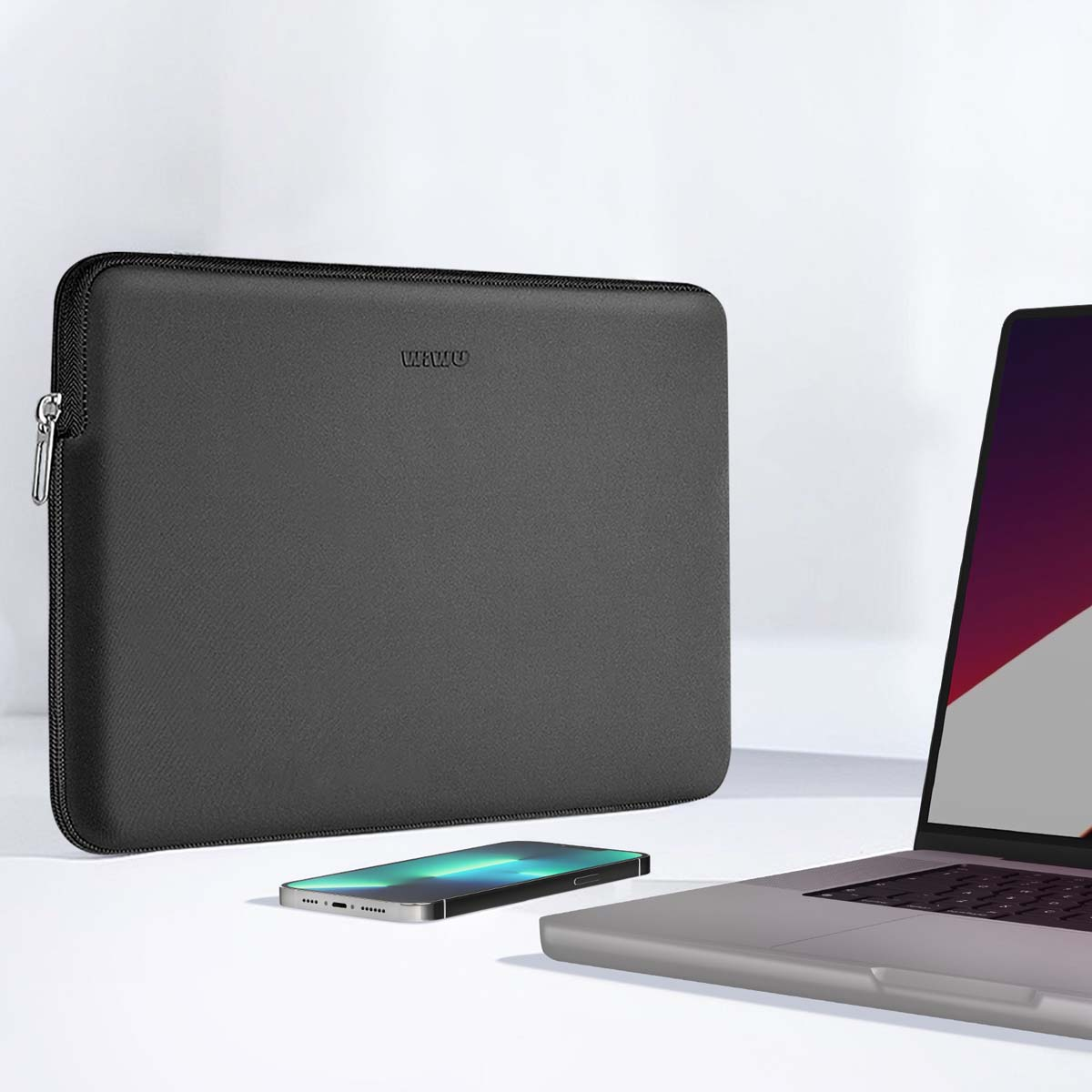 Una funda gris para portátil, teléfono y portátil sobre una superficie blanca. La funda tiene cremallera y la palabra WAWU.