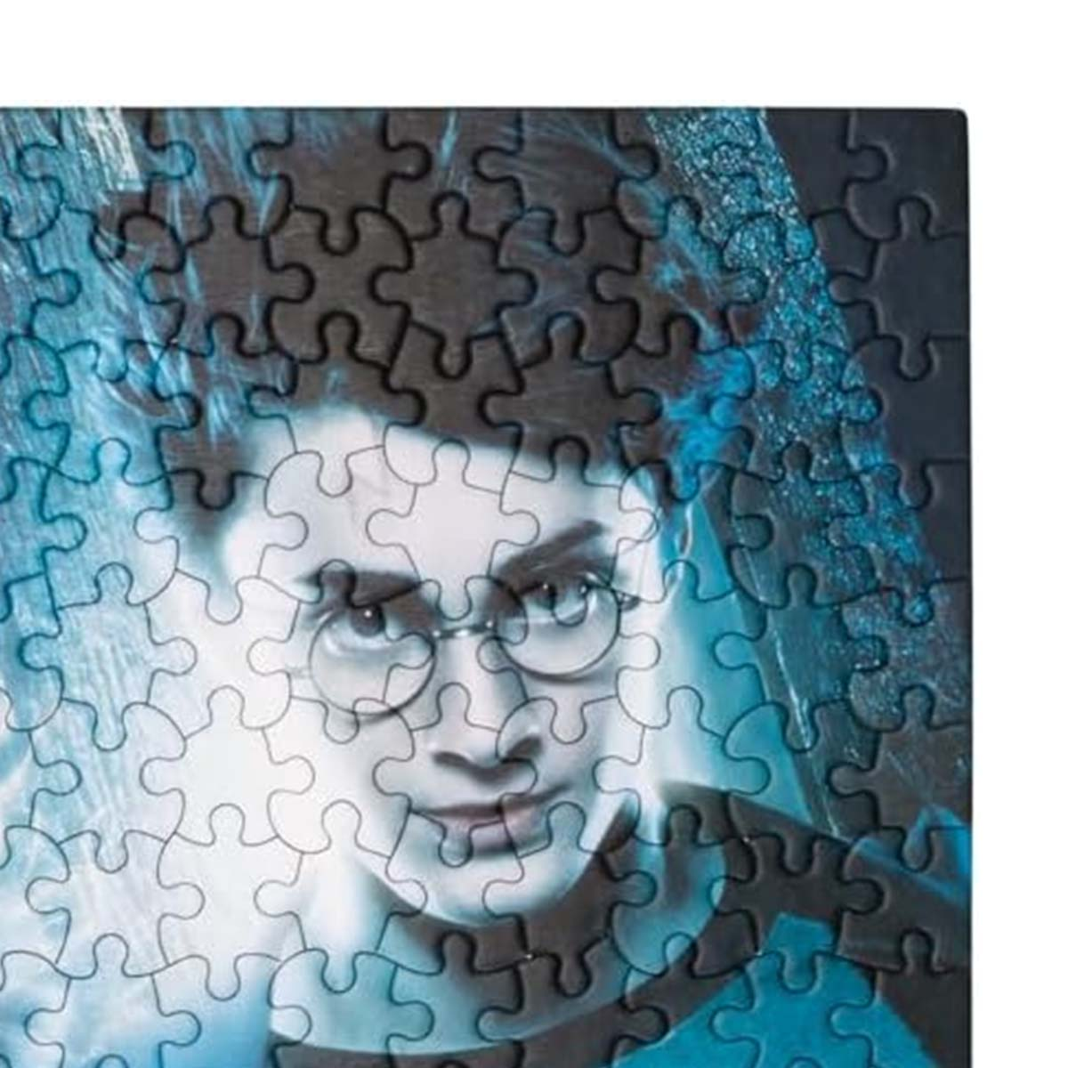 Un rompecabezas con la cara de Harry Potter. La imagen está oscurecida por piezas del rompecabezas. Lleva gafas y tiene cabello oscuro. El fondo es azul.