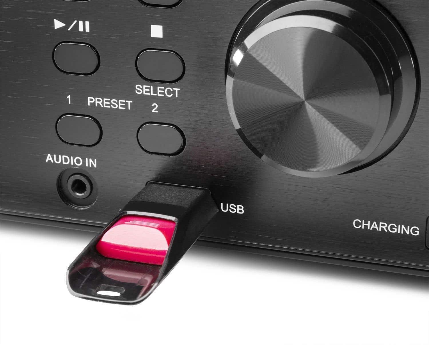 Nahaufnahme eines schwarzen Audiogeräts mit USB-Anschluss. Ein rosa USB-Stick ist eingesetzt. Knöpfe und ein großer Drehregler sind sichtbar.